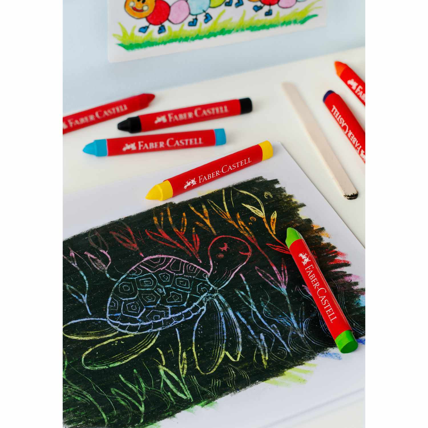 Wachsmalkreide Jumbo Box: Bunte Faber Castell Wachsmalkreiden auf Papier mit Schildkrötenzeichnung.