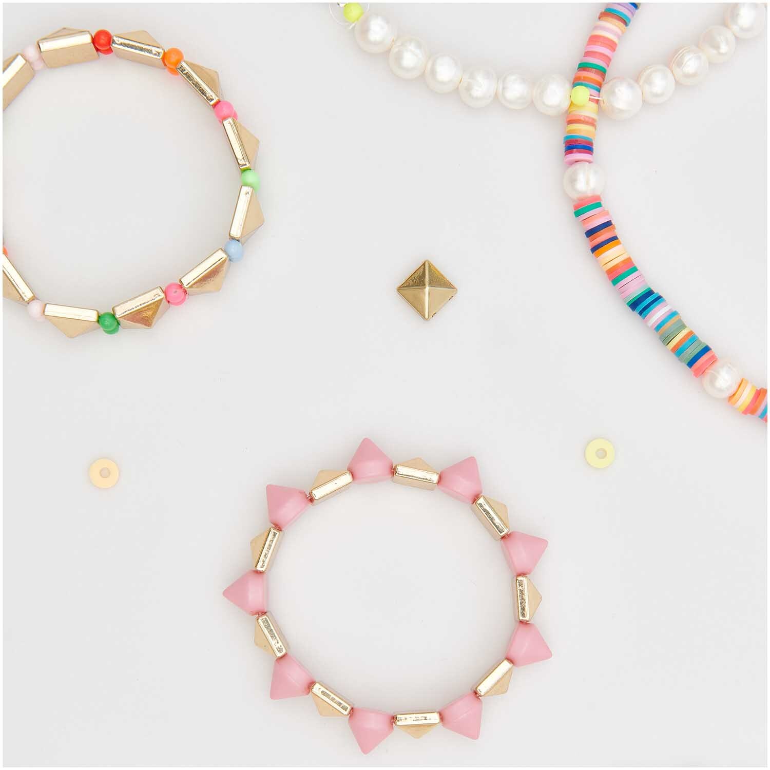 Gummischeiben Mix 6x1mm 60 Stück von Rico Design. Bunte Armbänder mit Perlen und geometrischen Formen auf hellem Hintergrund.