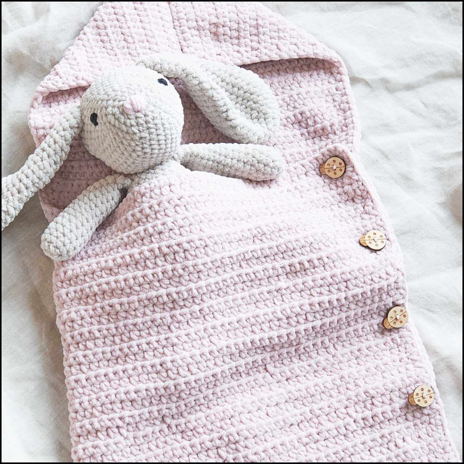 Holzknöpfe Tiere ll 4 Stück von Rico Design auf einer rosa gestrickten Babydecke mit Kuscheltier.