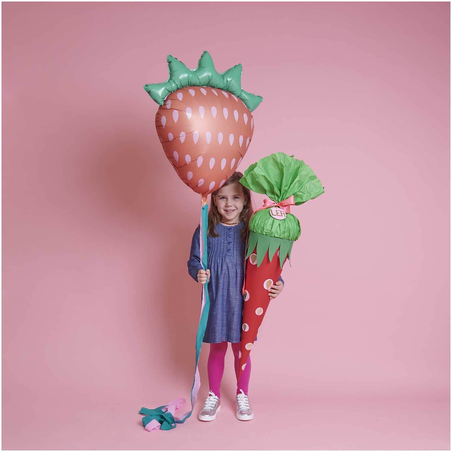 Moosgummimix 2mm 20x30cm 10 Stück: Kind in blauem Kleid mit großen, bunten Luftballons in Erdbeerform vor rosa Hintergrund.