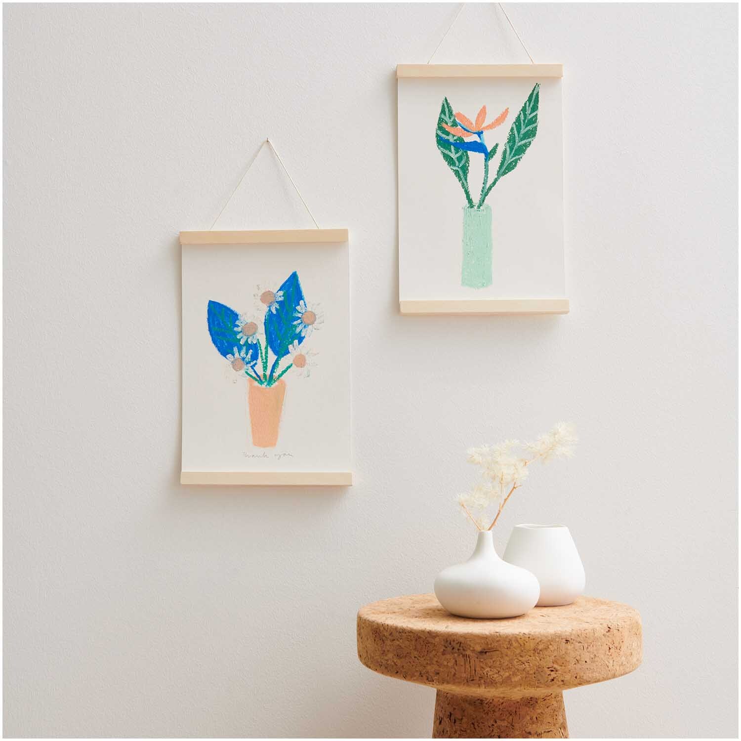Ölpastellkreide Neon 12 Farben: Zwei minimalistische Blumenbilder in Holzrahmen an einer weißen Wand.