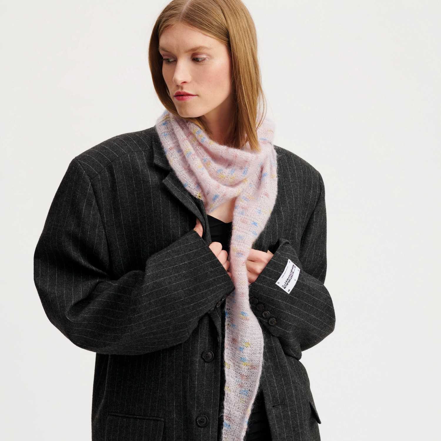 Strickset Dreieckstuch Modell 36: Frau trägt ein zartes, gestricktes Tuch über einem dunklen Blazer.