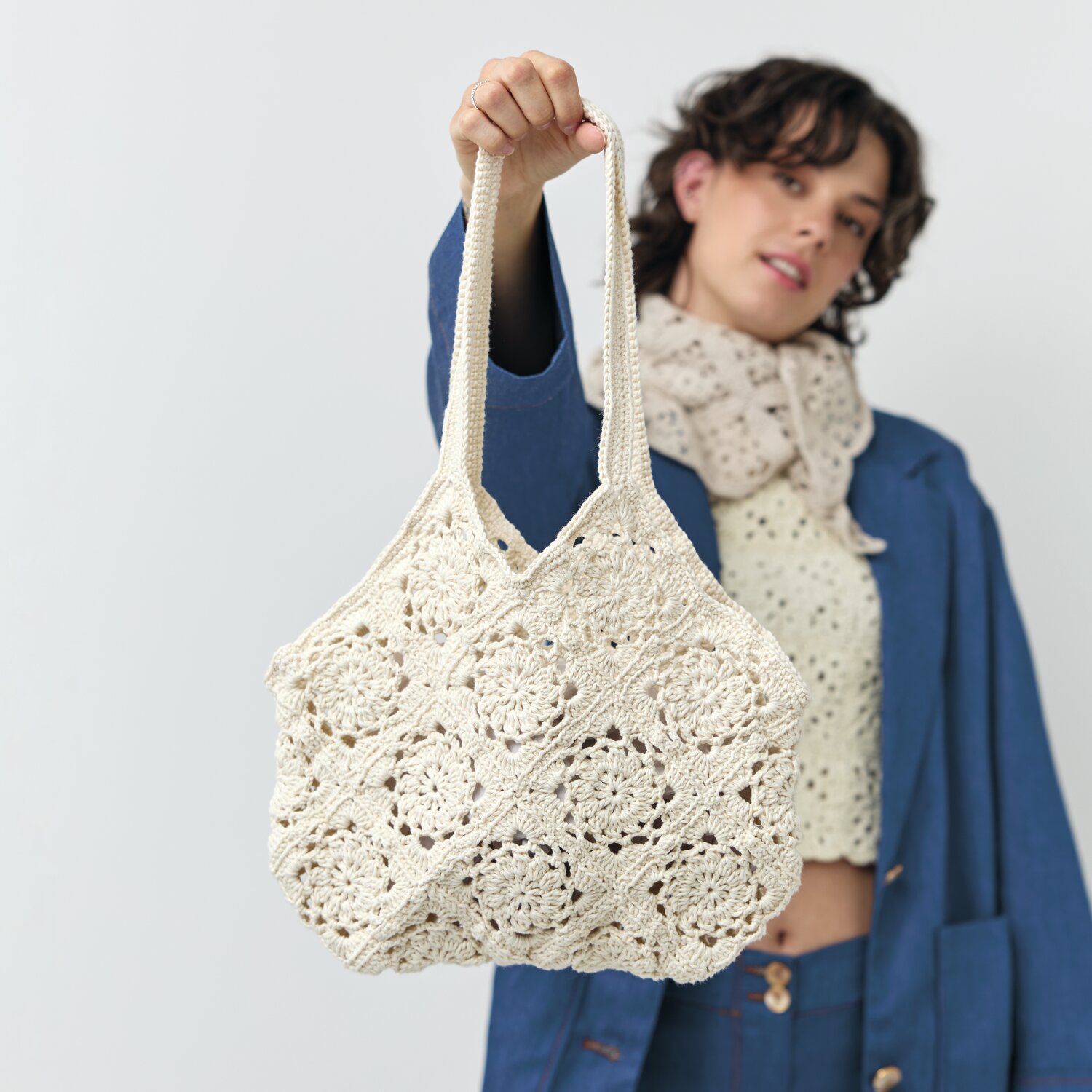 Häkelset Tasche Modell 03 aus Die Neue Masche No. 12, cremefarbene gehäkelte Tasche, gehalten von Frau in blauer Jacke.
