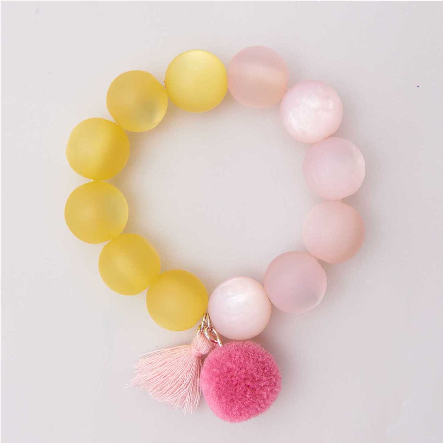 Pompons mit Öse 2cm 2 Stück von Rico Design, pink, an einem Armband mit gelben und rosa Perlen.