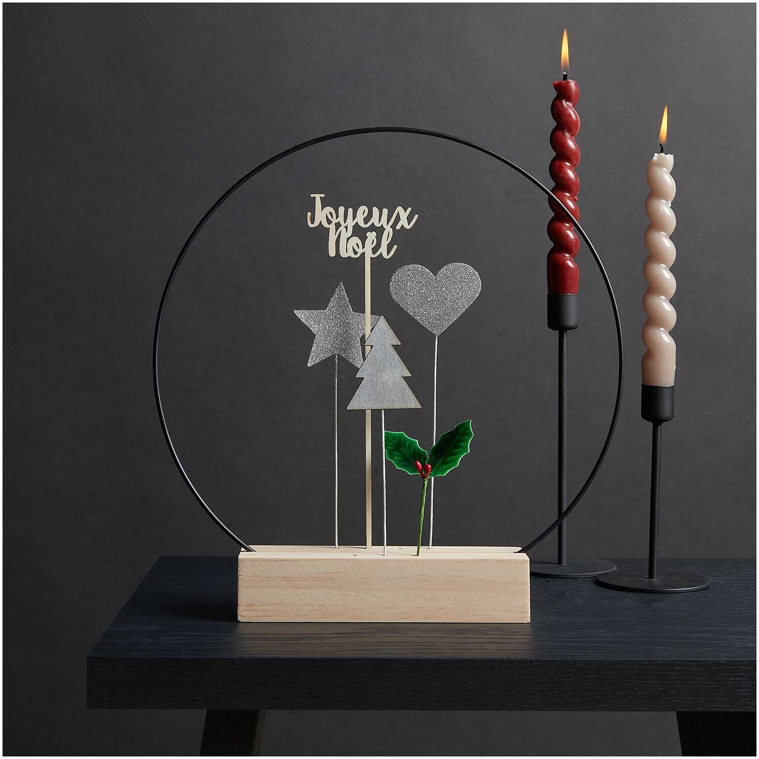 Holzpicker Joyeux Noel 25,3x6,5cm von Rico Design: Dekoration mit Stern, Herz und Tannenbaum auf Holzsockel, neben zwei gedrehten Kerzen.