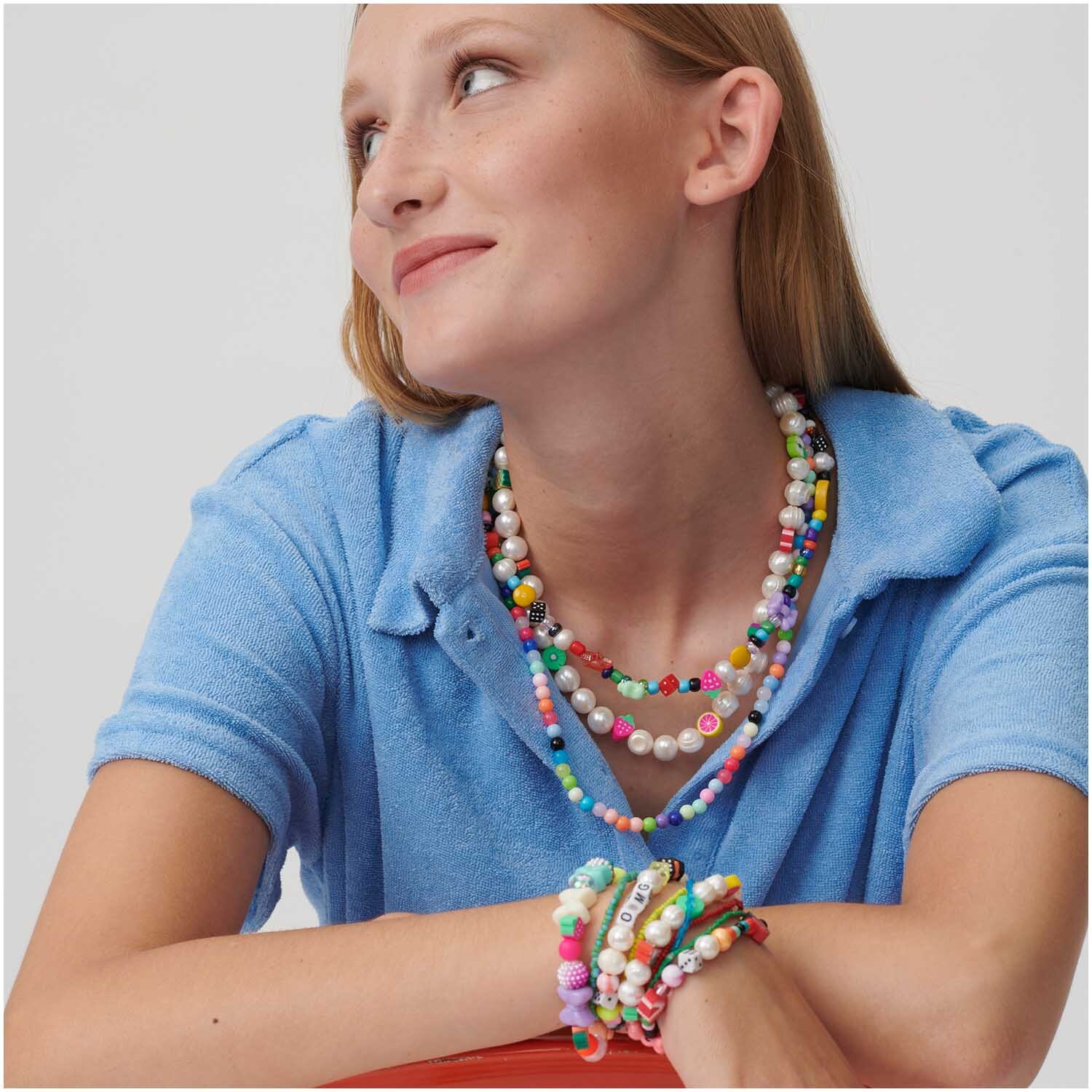 itoshii Perlen Bundle Farbverlauf 11mm 20 Stück, getragen von Frau in blauem Oberteil, zeigt bunte Halsketten und Armbänder.