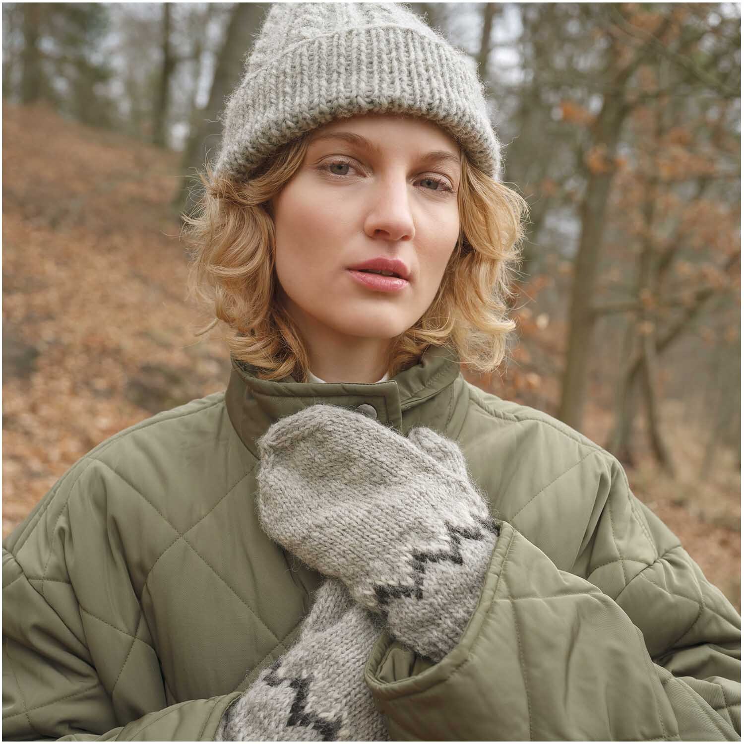 Strickset Mütze Modell 03 aus Luxury Knits Winter Special: Frau trägt graue Mütze und passende Handschuhe im Wald.