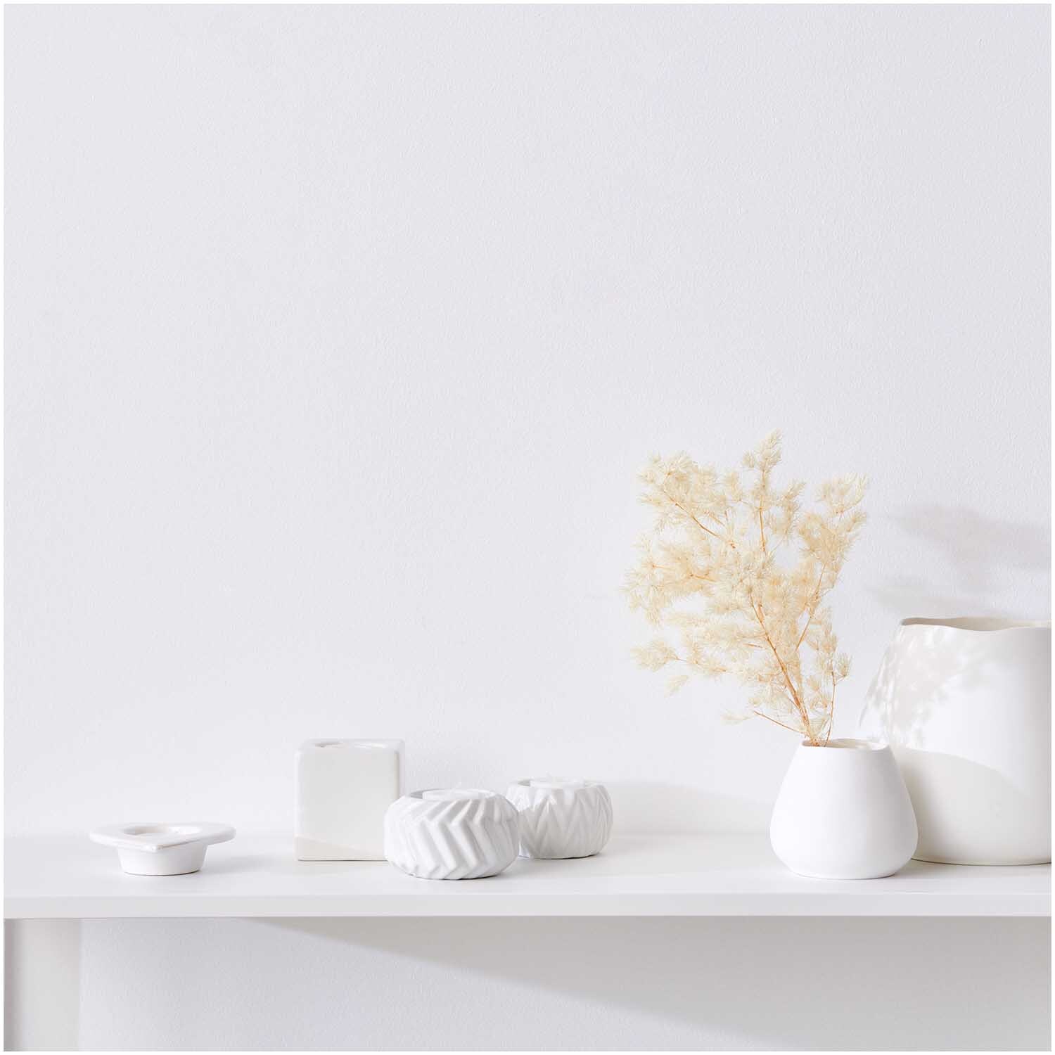 Porzellan-Teelichthalter von Rico Design auf einem weißen Regal, umgeben von minimalistischen Vasen und Dekorationen.