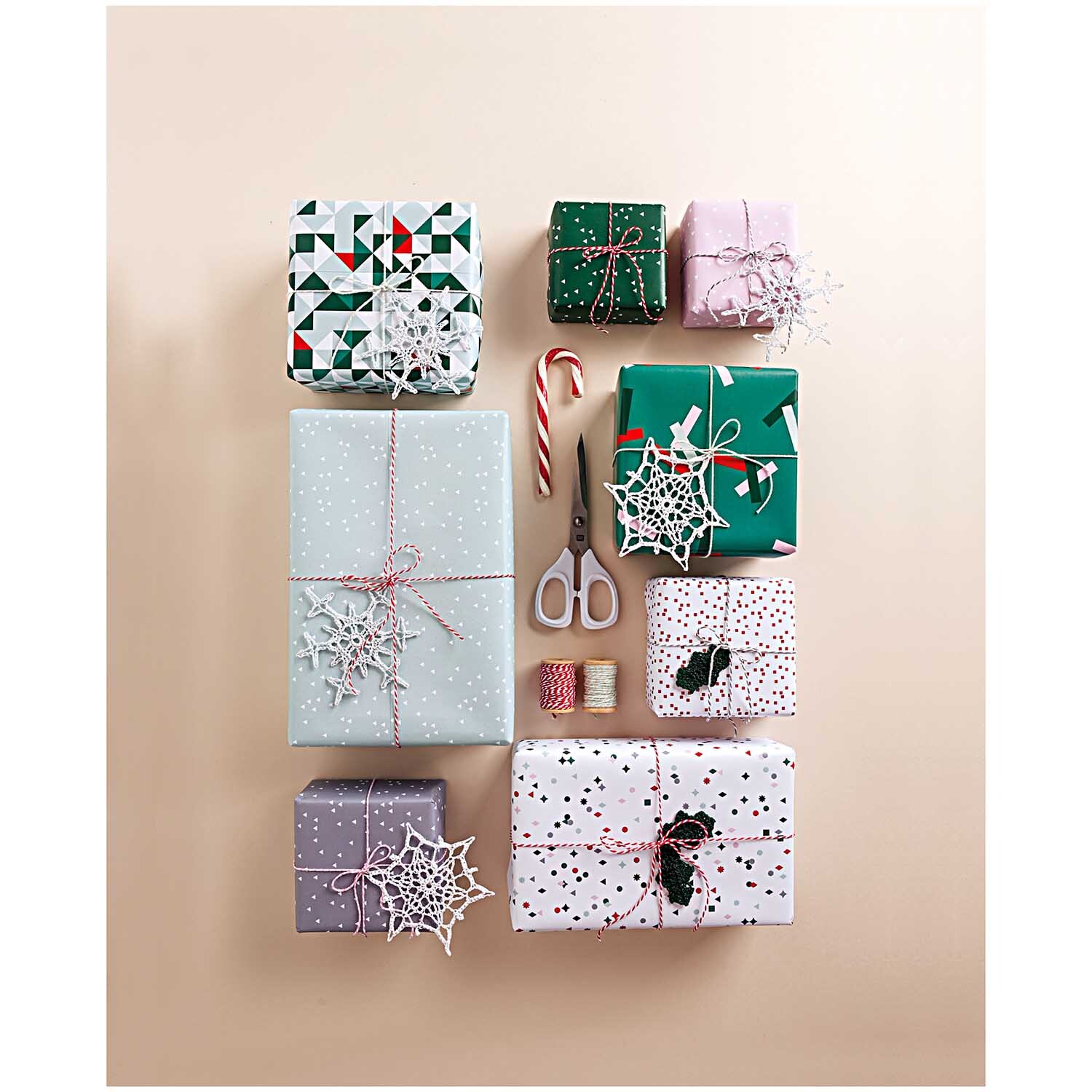 Paper Poetry Baumwollgarn in rosa-weiß, dekorativ um Geschenkboxen gewickelt, mit Schere und Zuckerstange.