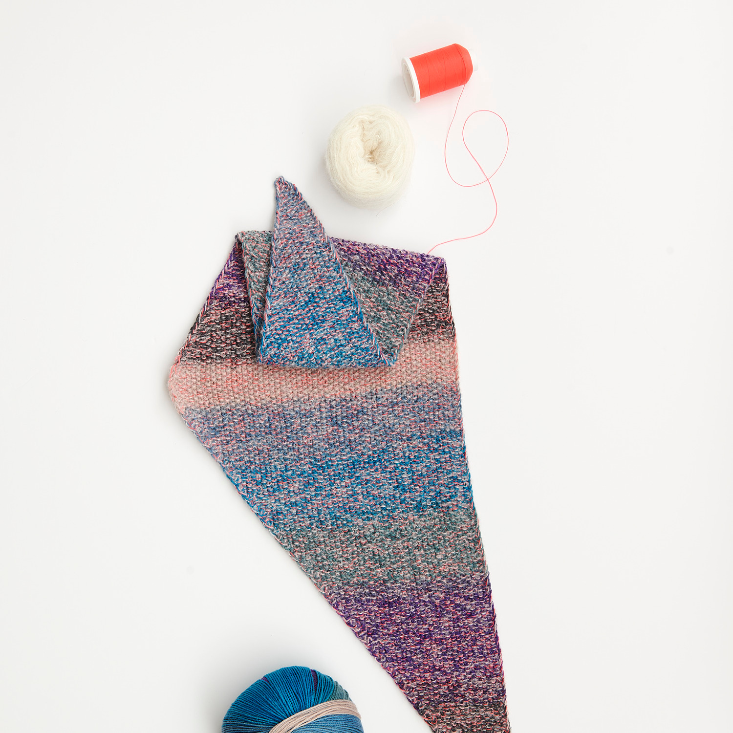 Mini Tücher Special: Buntes Strickstück mit Garnrollen in Blau und Weiß auf weißem Hintergrund.