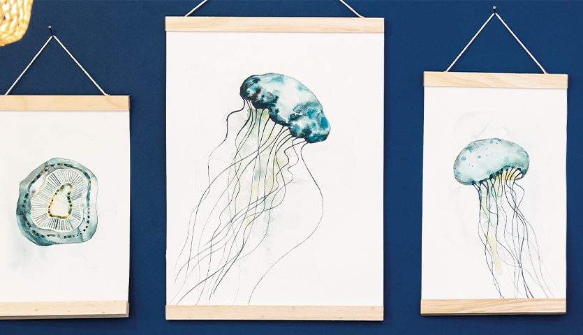 Anleitung Quallen aquarellieren: Drei Bilder von Quallen in Aquarelltechnik an blauer Wand.