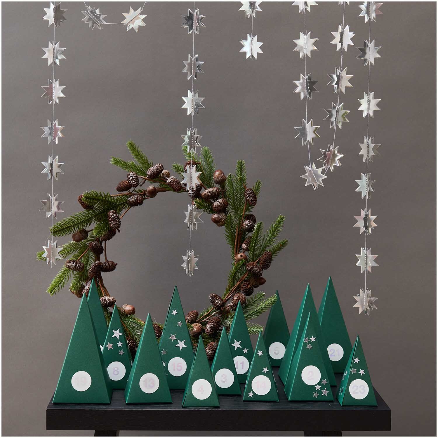 Paper Poetry Adventskalender Sticker Zahlen 1-24 vor einem dekorativen Hintergrund mit Tannenzweigen und Sternen.