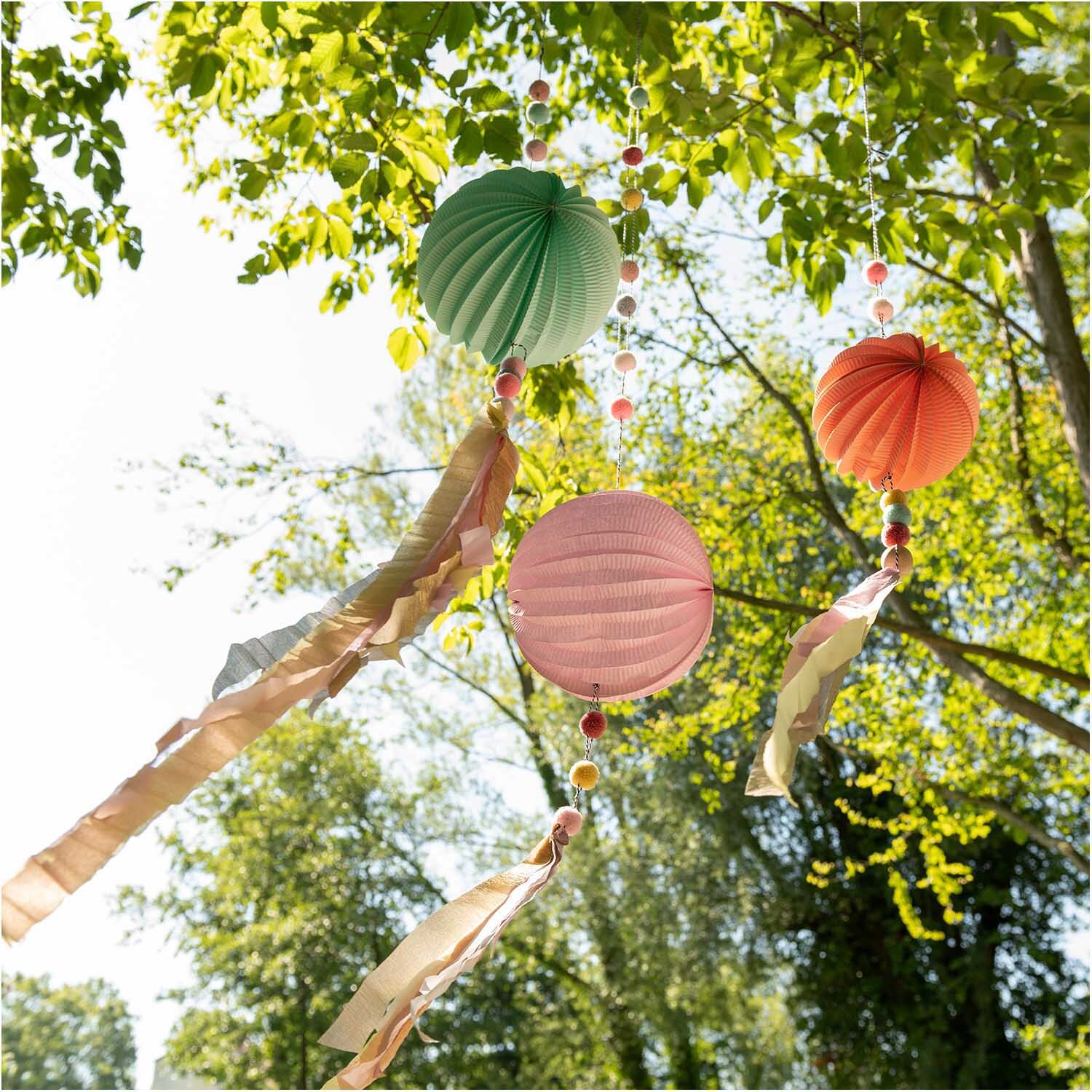 Garn Pompons 24 Stück: Bunte Pompons von Rico Design hängen dekorativ an einem Baum im Freien.