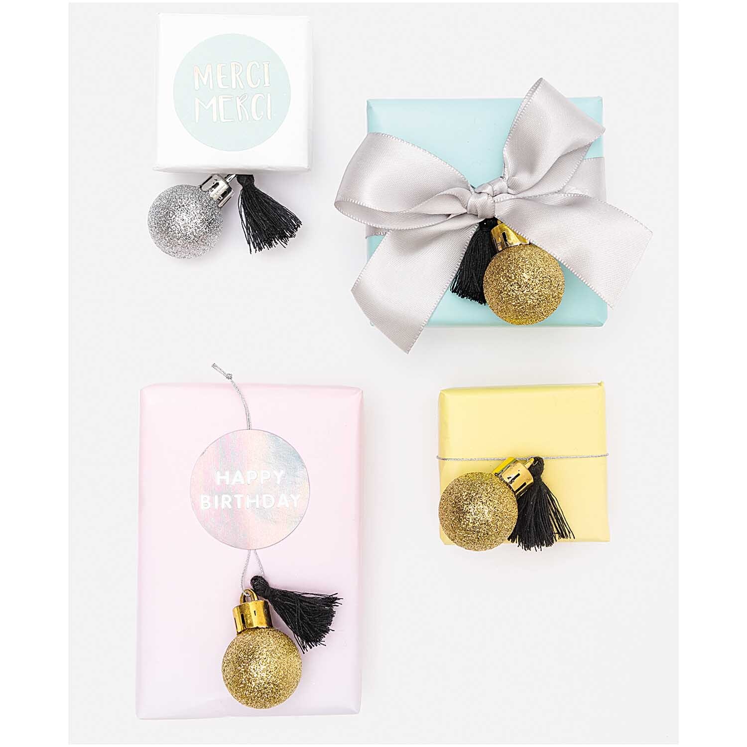 Mini-Kugel-Anhänger gold-silber 6 Stück, dekorativ auf Geschenkboxen in Pastellfarben arrangiert.