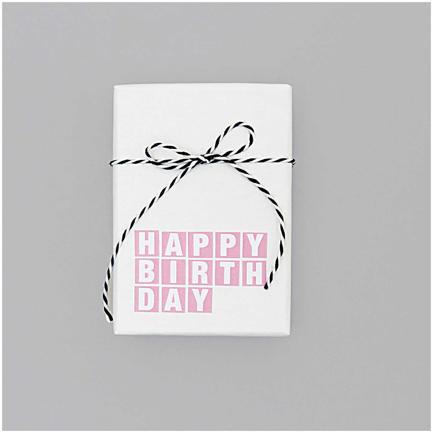 Paper Poetry Baumwollgarn schwarz-weiß 15m, dekorativ um ein Geschenk mit rosa "Happy Birthday"-Aufschrift gebunden. Ideal für kreative Verpackungen.