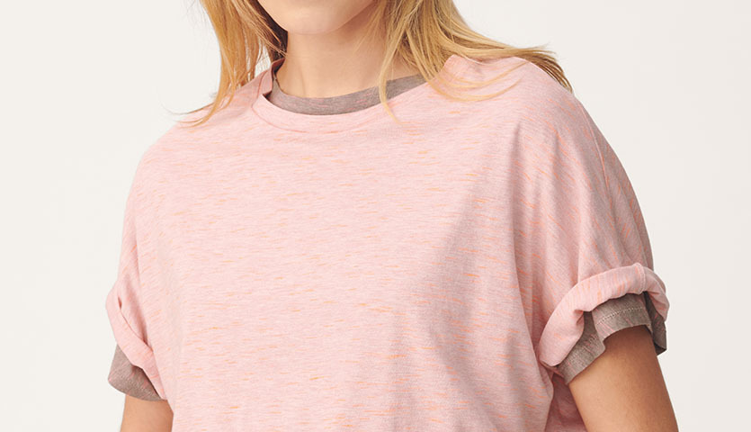 Nähanleitung Shirt aus Jersey: Frau trägt ein lässiges, rosa Jersey-Shirt mit umgeschlagenen Ärmeln.