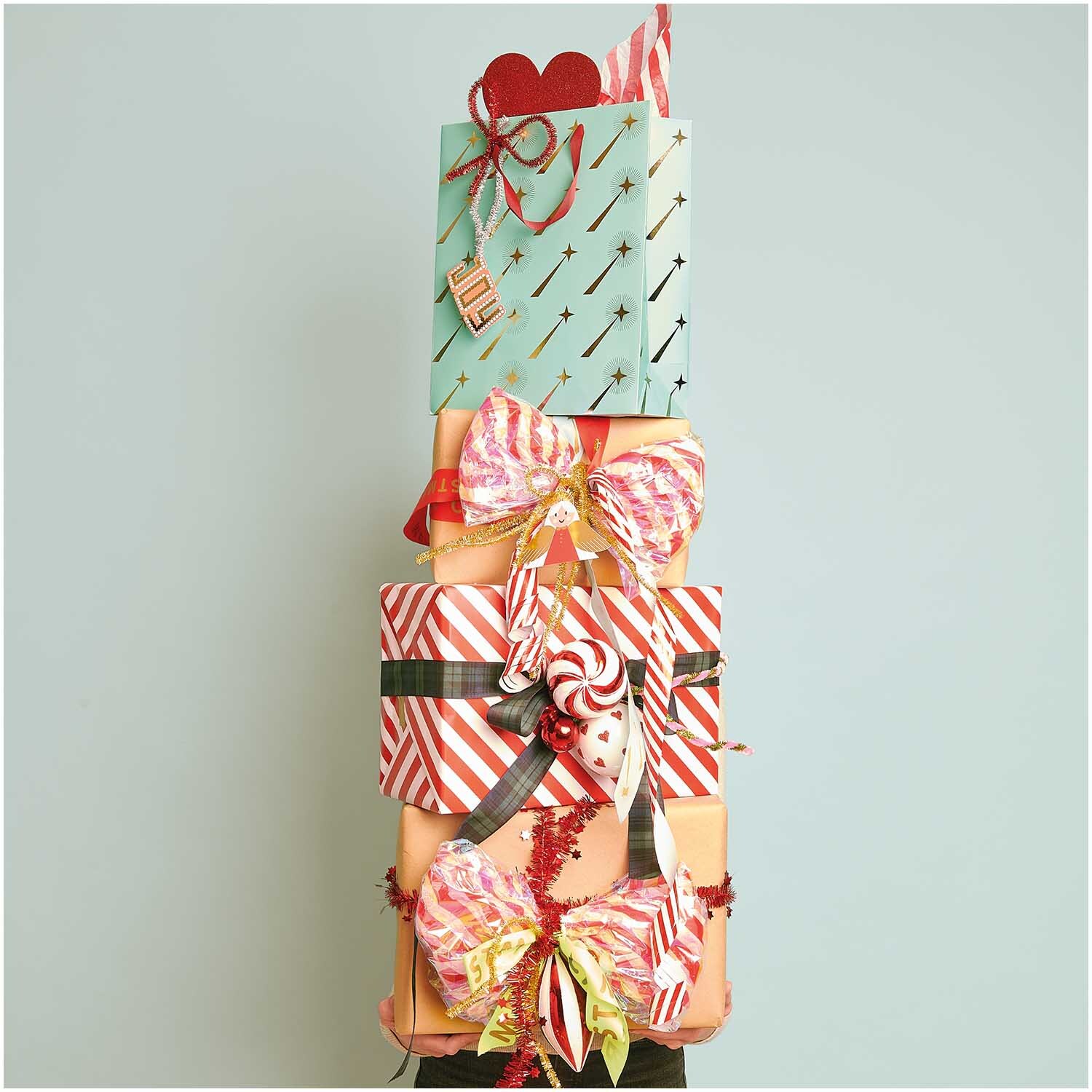 Paper Poetry Geschenkpapier zeigt rote und weiße Streifen auf Geschenken mit bunten Schleifen.