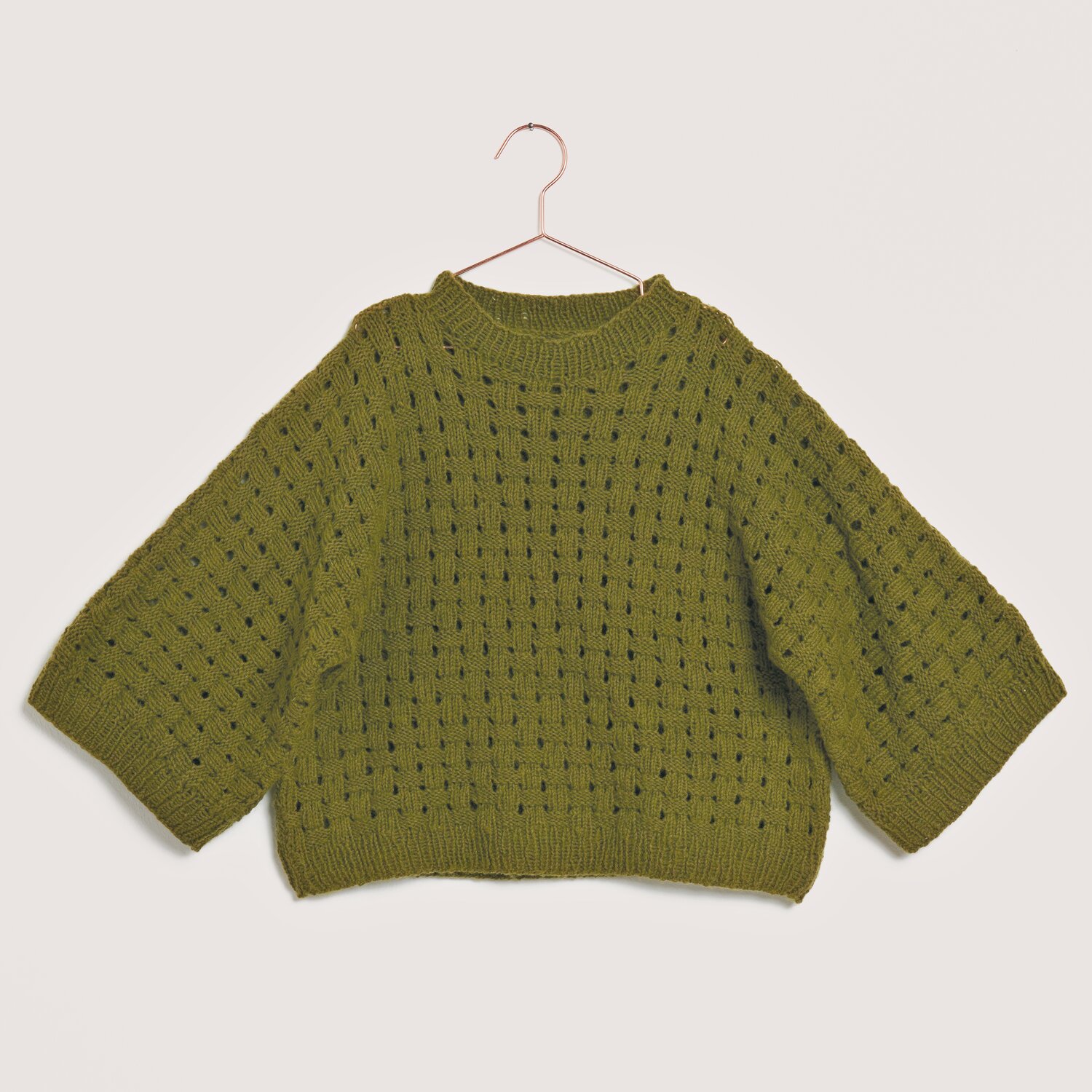 Made by Me No. 22 Frühjahr-Sommer Pullover in Oliv mit weitem Schnitt, gestrickt aus Creative Cotton Fleece dk, präsentiert auf einem Kleiderbügel.