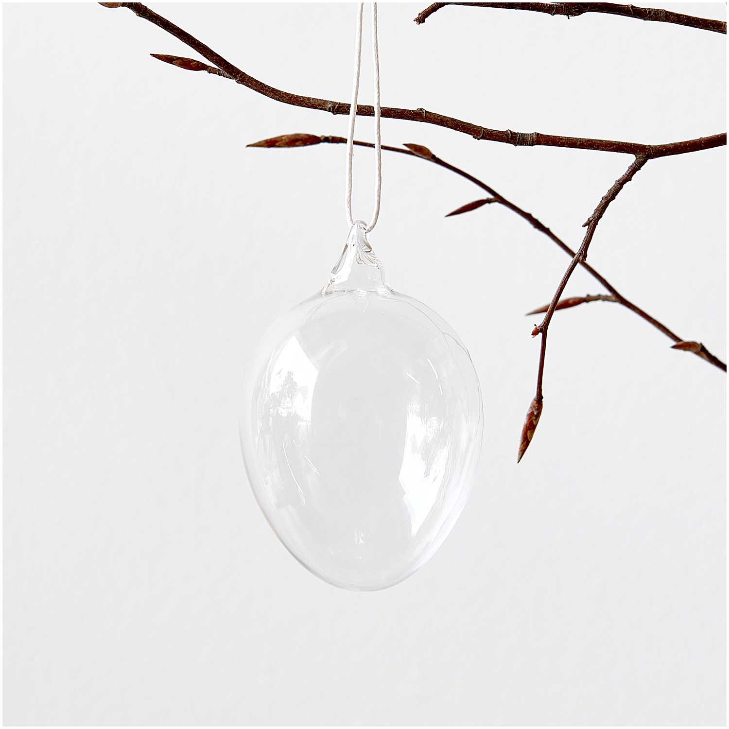 Glas Ei transparent Ø 7cm von Rico Design hängt an einem Ast, minimalistisches Design.