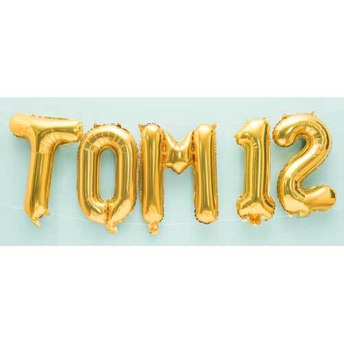 Folienballon Buchstabe gold 36cm: Goldene Buchstabenballons bilden "TOM 12" vor einem hellblauen Hintergrund.