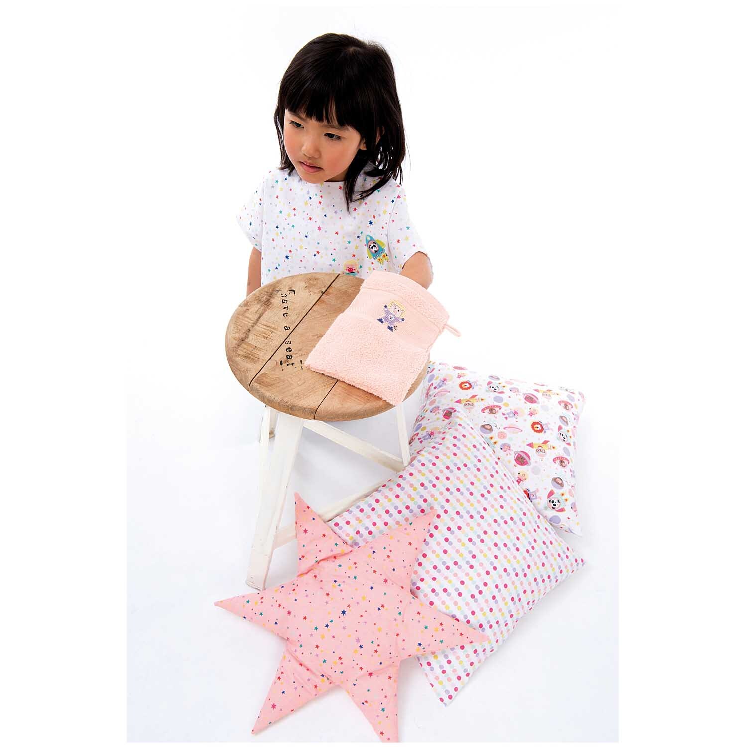 Tiere im Weltall Stoff rosa 50x140cm: Kind mit rosa Kissen und Stoffen von Rico Design auf Hocker.