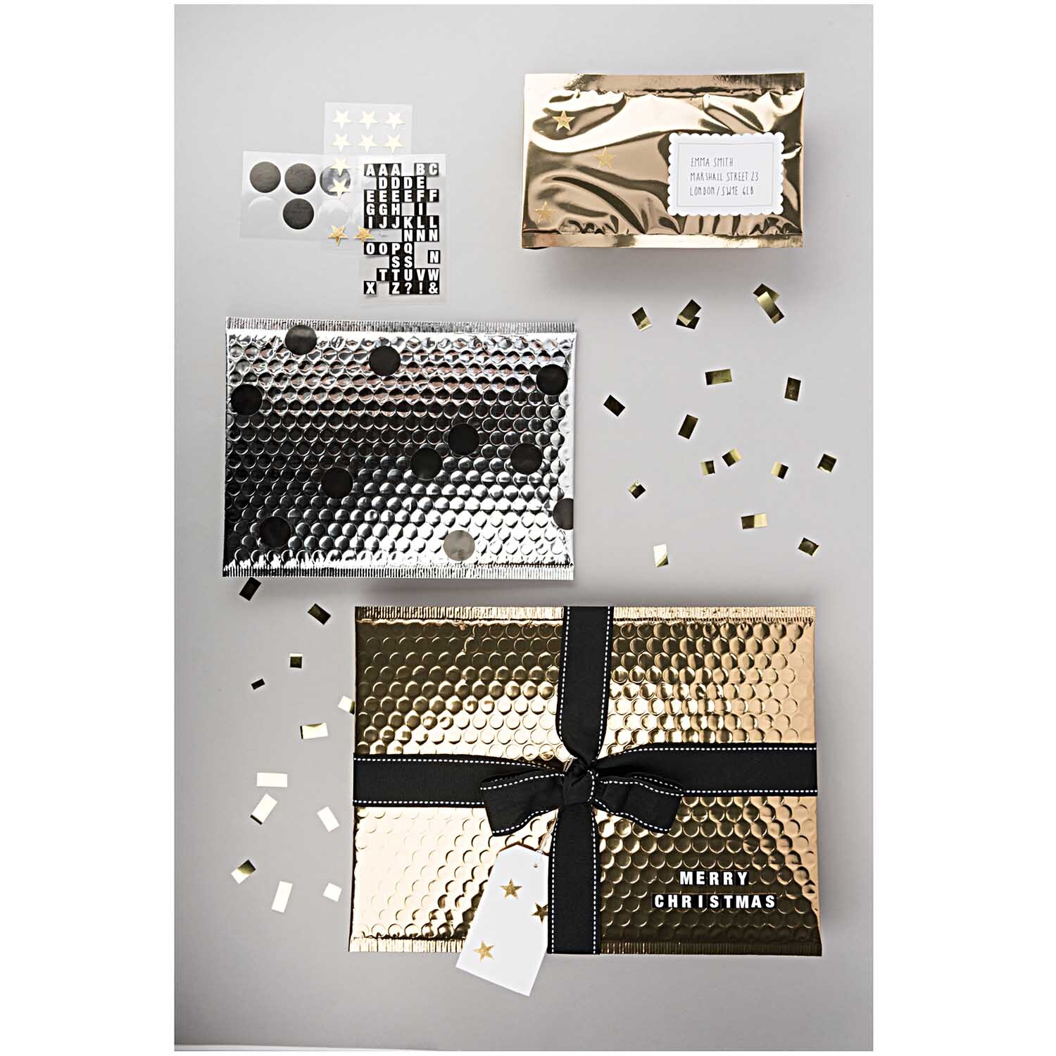 Luftpolstertasche B5 in Gold von Rico Design, dekoriert mit schwarzem Band und Weihnachtsmotiv.