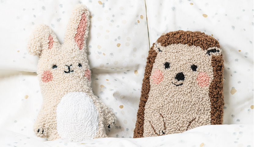 Punch Needle Anleitung Hase: Zwei gestrickte Kuscheltiere, ein Hase und ein Igel, auf einem gepunkteten Hintergrund.