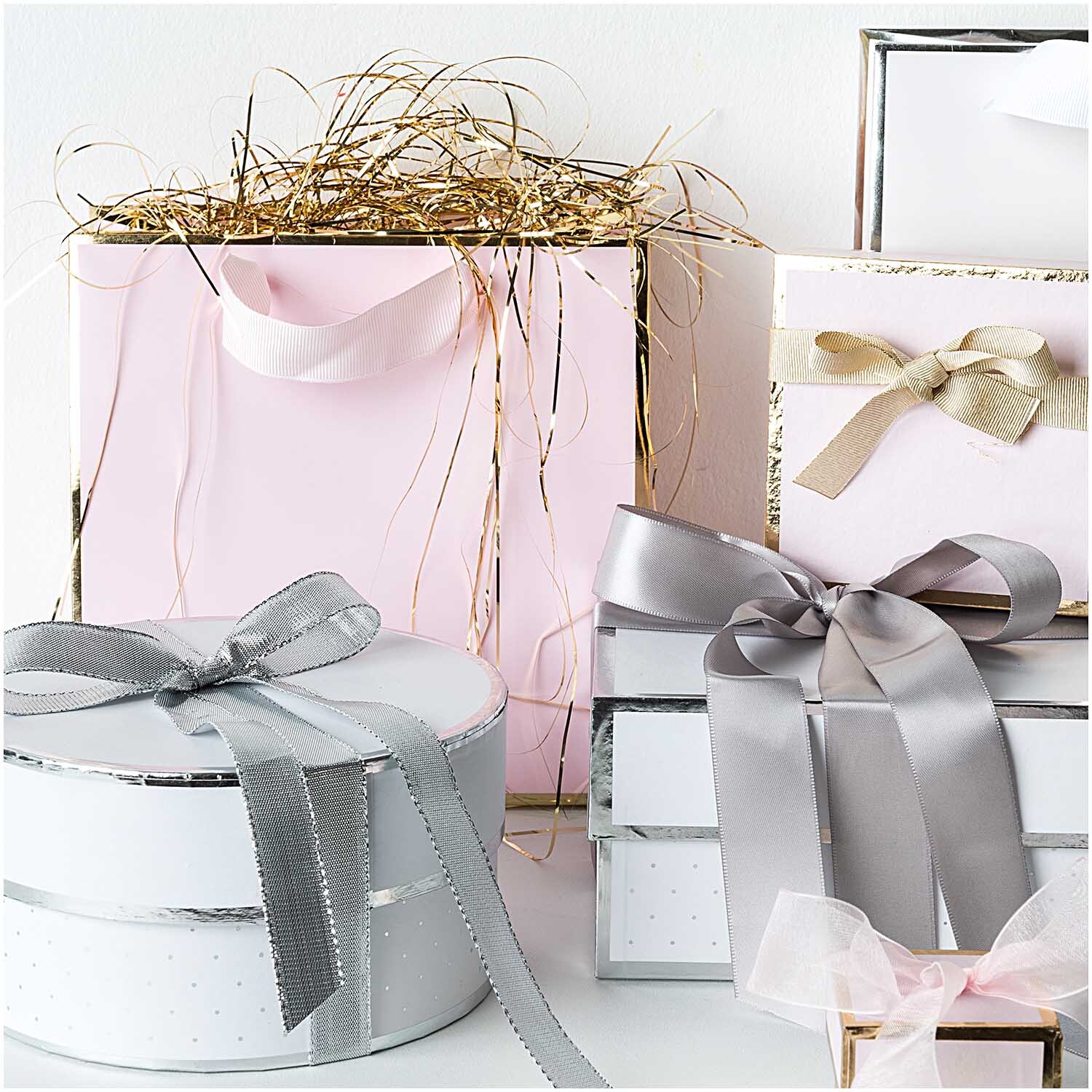 Paper Poetry Geschenkschachtel eckig rosa von Rico Design, umgeben von eleganten Geschenkboxen mit Schleifen. Ideal für stilvolle Präsentationen.
