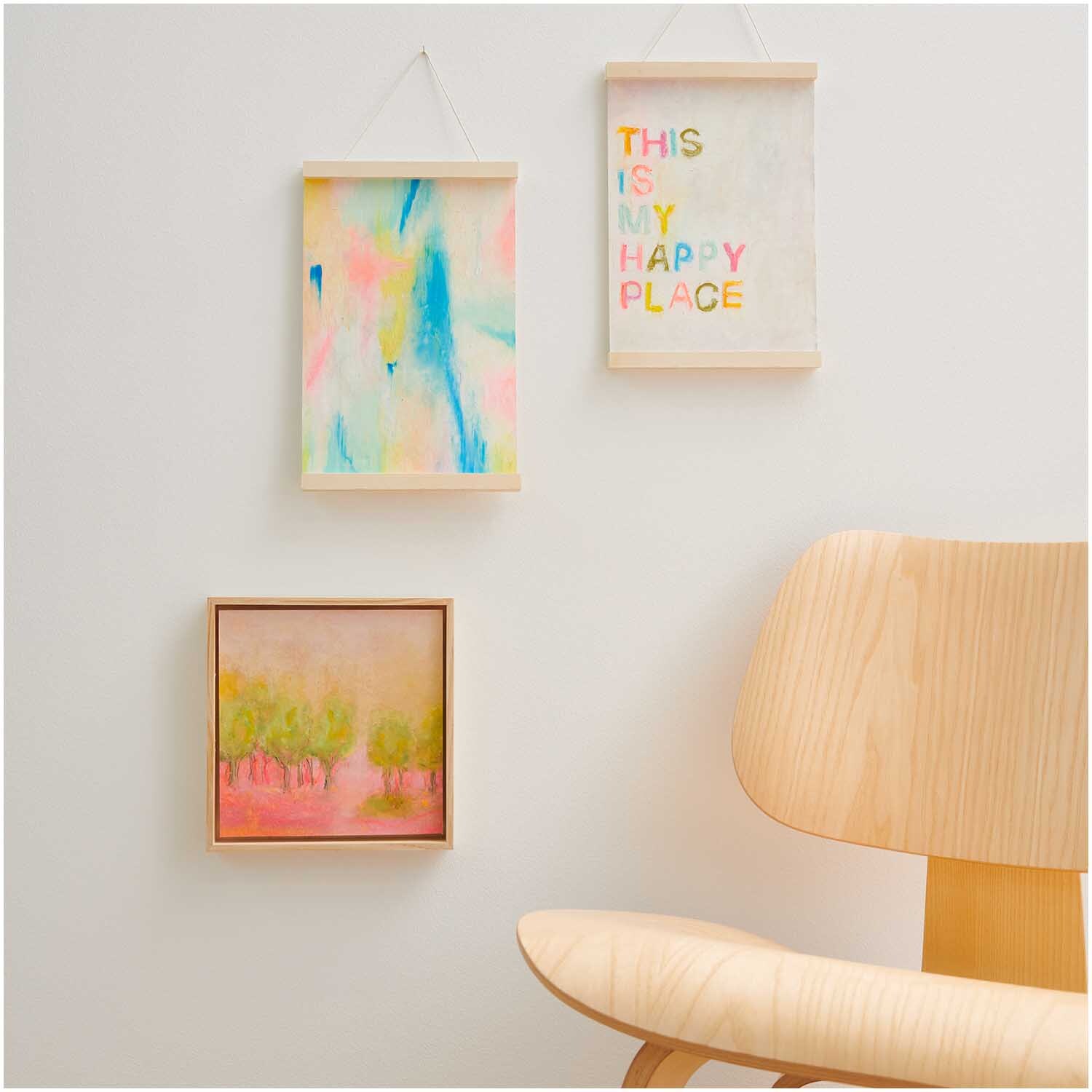 Ölpastellkreide Pastell & Neon 12 Farben von Rico Design: Drei bunte Kunstwerke an einer weißen Wand, neben einem hellen Holzstuhl.