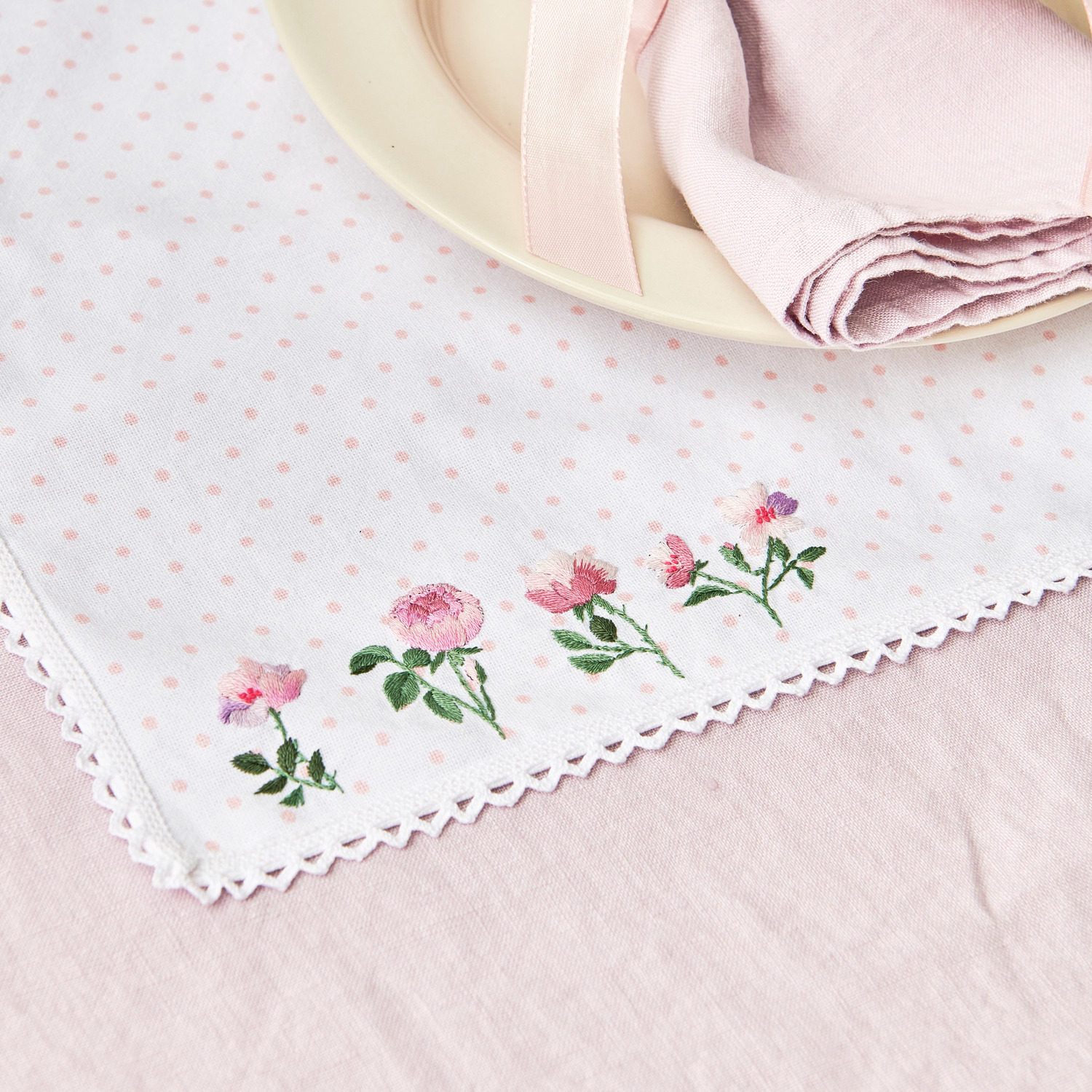 Stick and Stitch Rosen: Weißes Deckchen mit rosa Punkten und Rosenstickerei, ideal für elegante Tischdekoration.