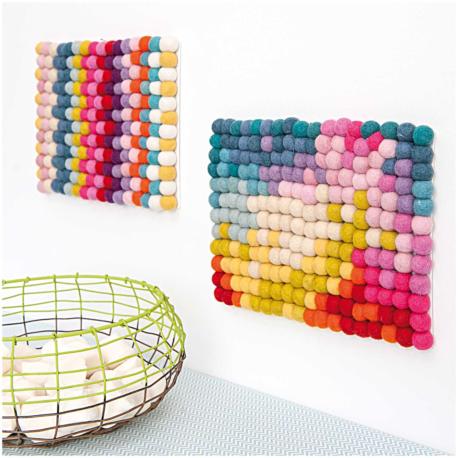 Filz-Kugelmix 1,5cm 20 Stück: Bunte Filzkugeln von Rico Design, dekorativ an der Wand arrangiert.