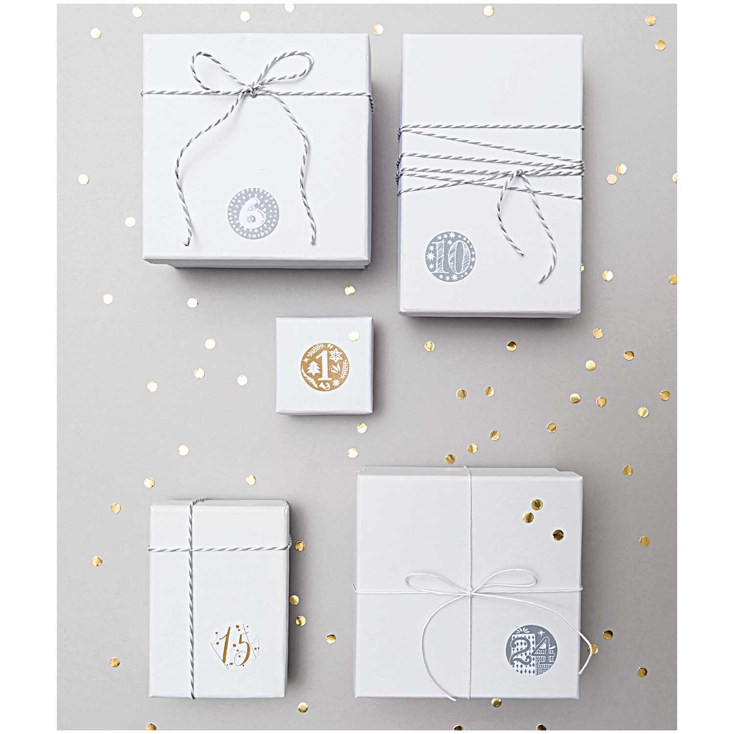 Paper Poetry Adventskalender Sticker verzieren weiße Geschenke mit goldenen und silbernen Motiven. Perfekt für festliche Dekorationen.