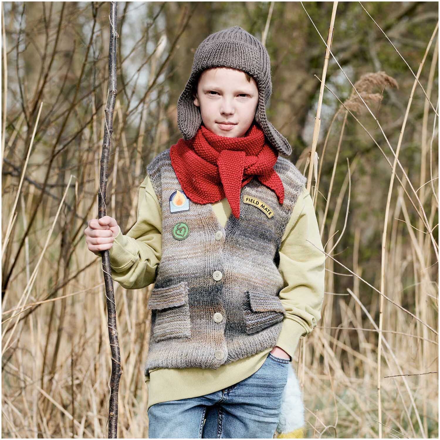 Creative Melange Garzato aran Wonderball: Kind im Freien mit gestrickter Weste und rotem Schal.