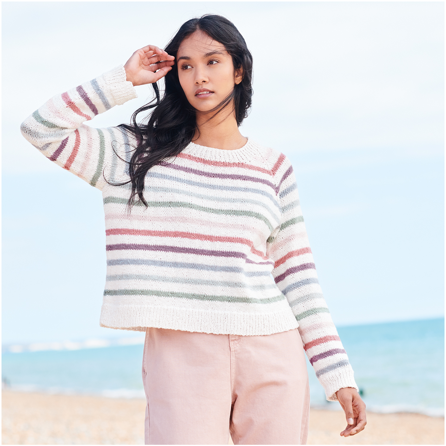 Strickset Pullover Modell 14 aus Lovewool Nr. 18, gestreift in Pastelltönen, am Strand getragen.