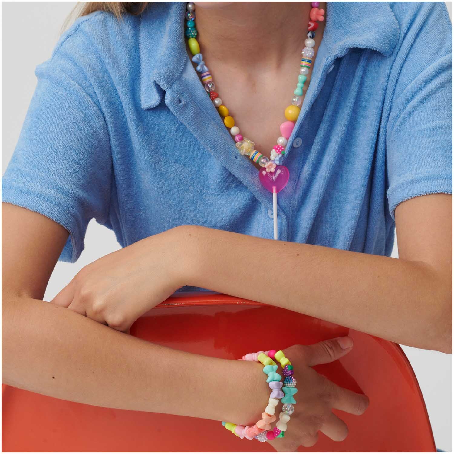 itoshii Gestreifte Zylinderperlen in pastellfarbenem Regenbogen-Design, getragen als bunte Halskette und Armband.