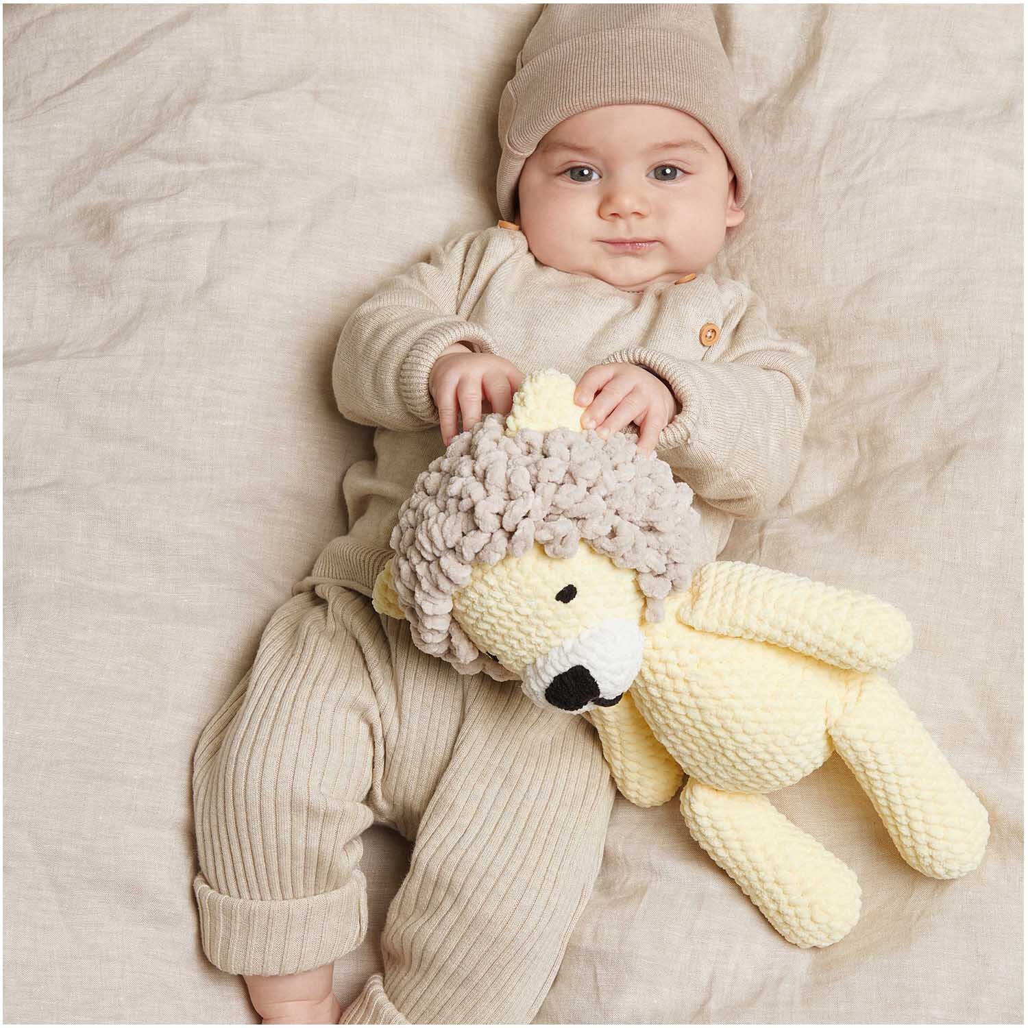 Creative Chenillove: Ein Baby in beiger Kleidung hält ein vanillefarbenes Kuscheltier aus Rico Design Wolle.