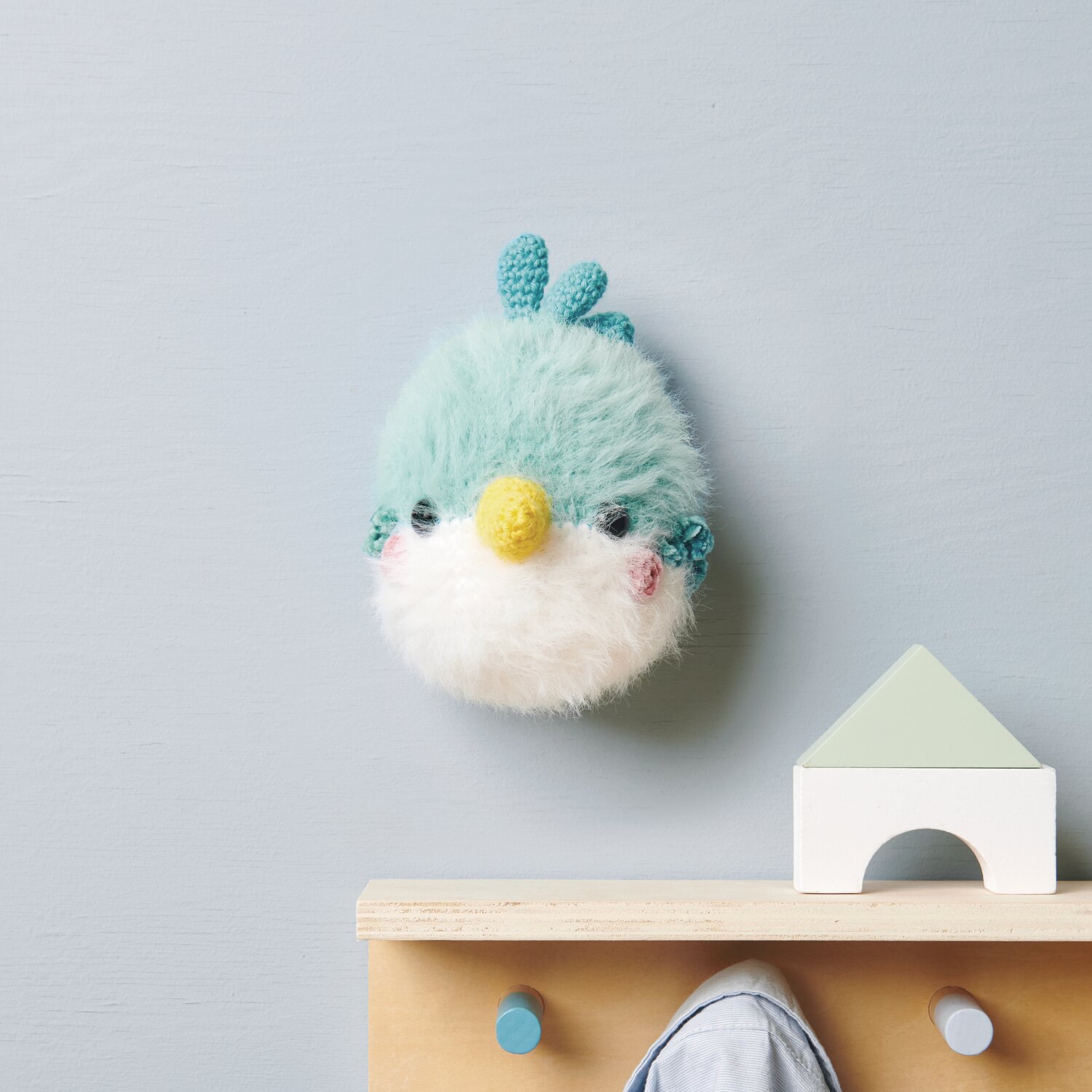 Ricorumi Furry Animals: Flauschiger türkis-weißer Vogel mit gelbem Schnabel an blauer Wand.