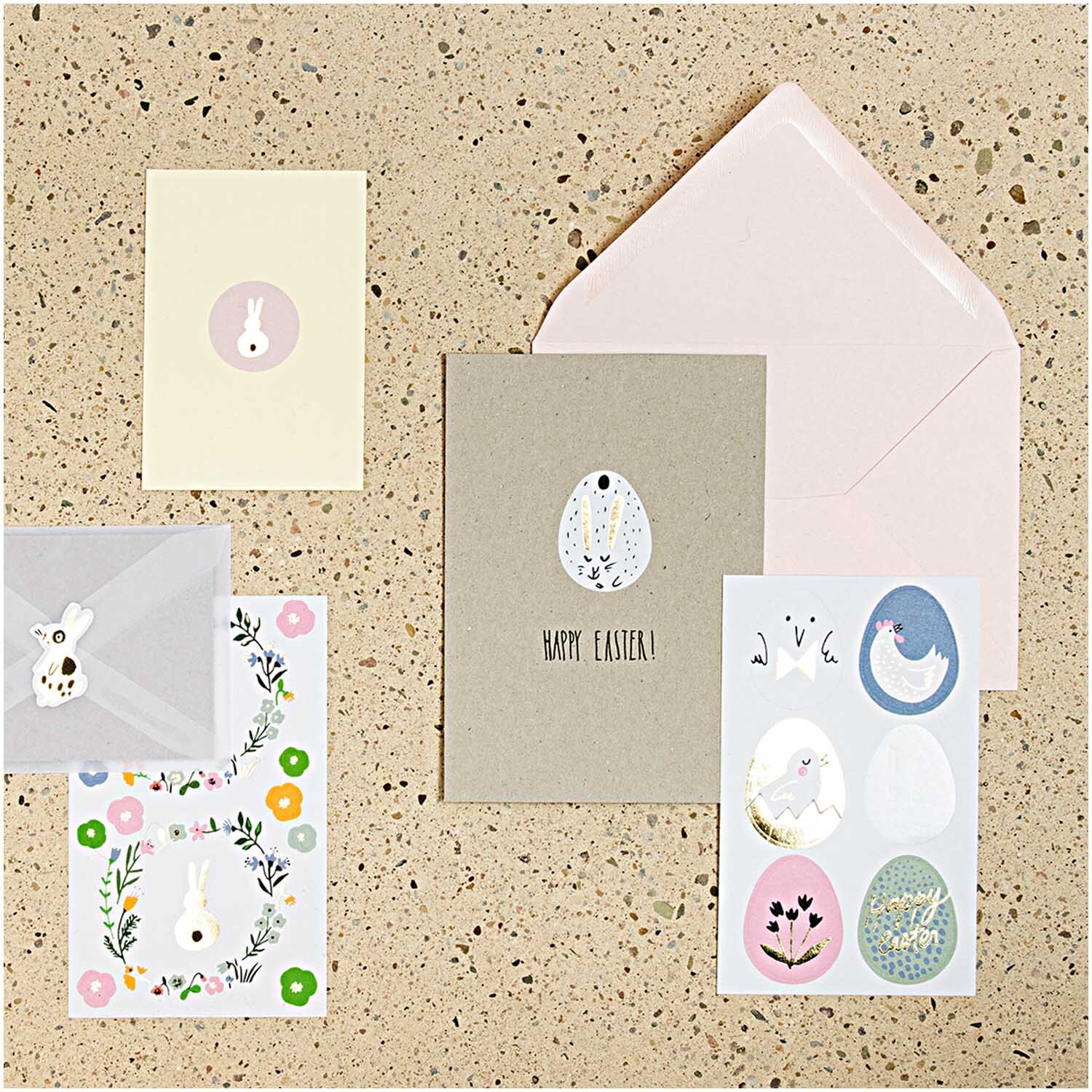 Paper Poetry Sticker Bunny Hop Ostereier 24 Stück: Osterkarten und Umschläge mit bunten Stickern von Rico Design auf einem Tisch arrangiert.