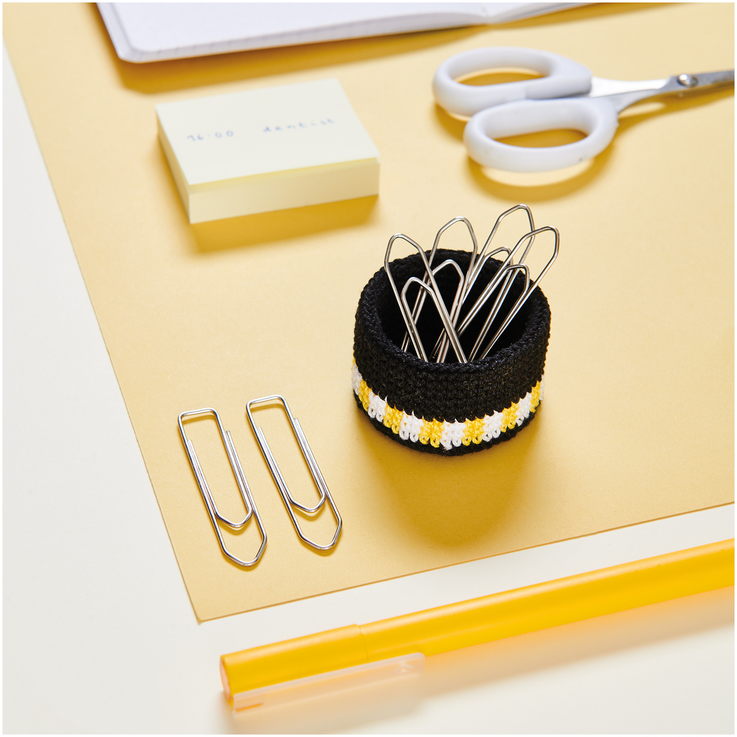 Essentials Crochet: Ein weißer, gehäkelter Stifthalter von Rico Design auf einem Schreibtisch mit Büroklammern und Schere.