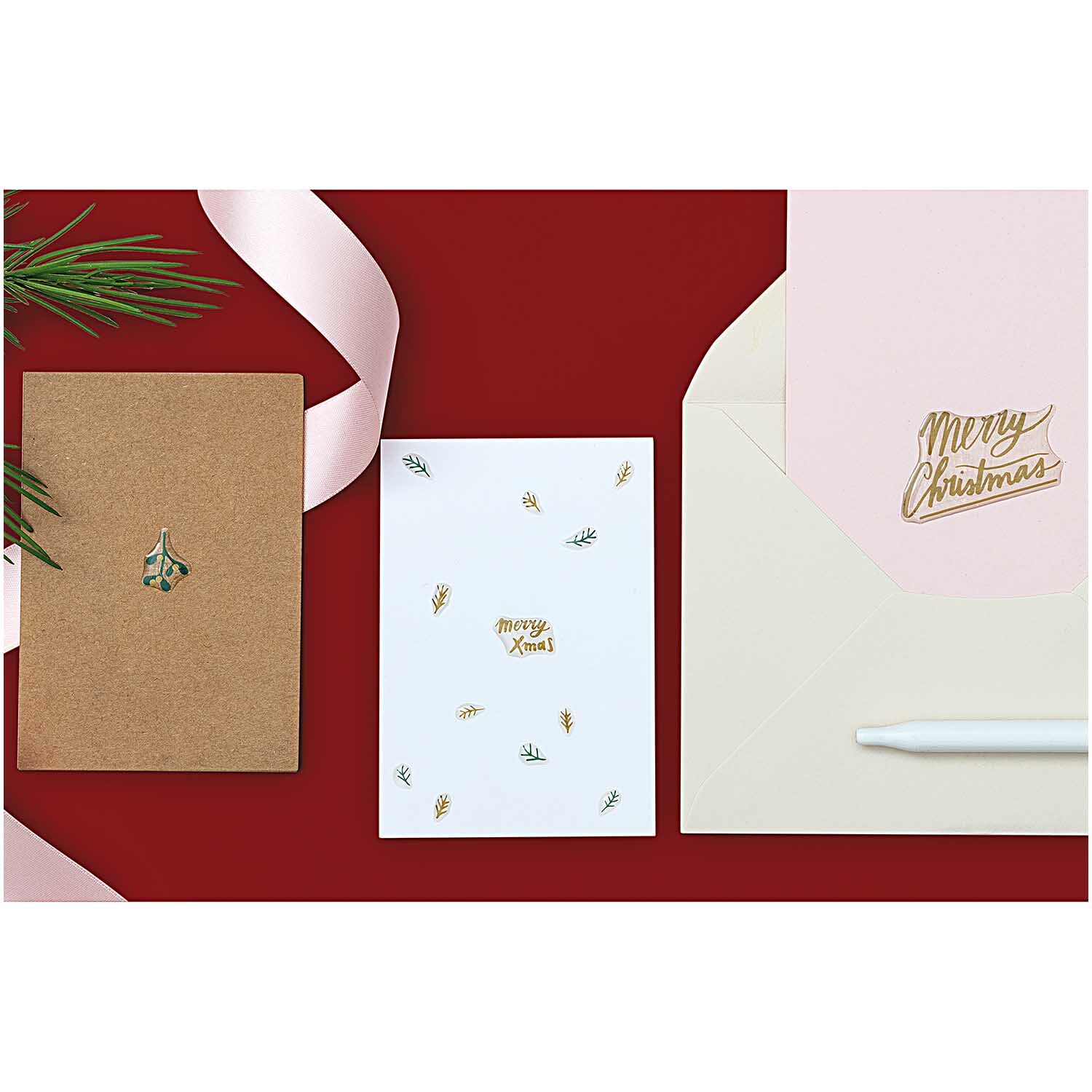Paper Poetry Gelsticker Jolly Christmas Schrift auf Karten und Umschlägen, dekoriert mit festlichen Motiven auf rotem Hintergrund.