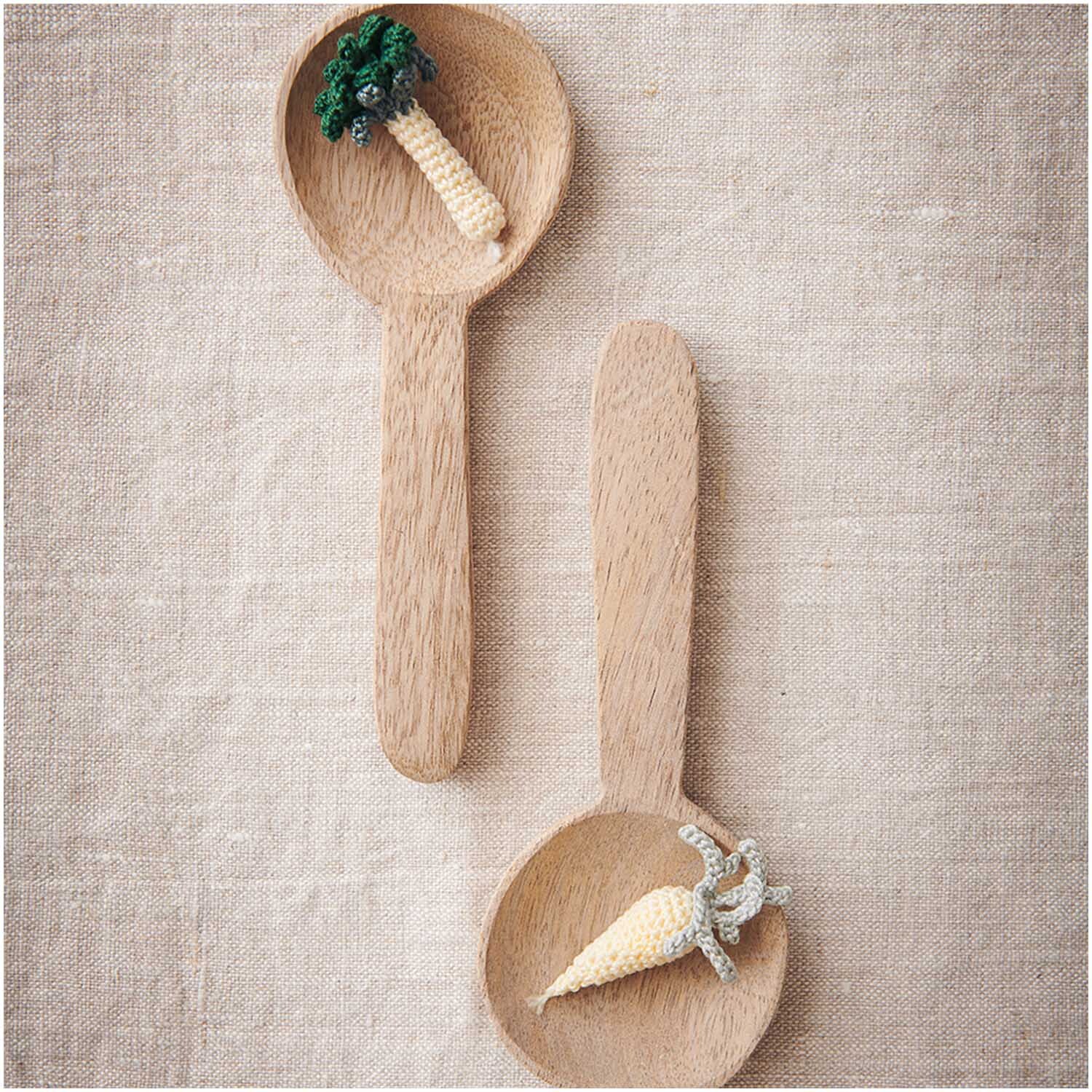 Essentials Crochet: Zwei Holzlöffel mit gehäkeltem Gemüse auf Leinenstoff, Farbe Vanille.