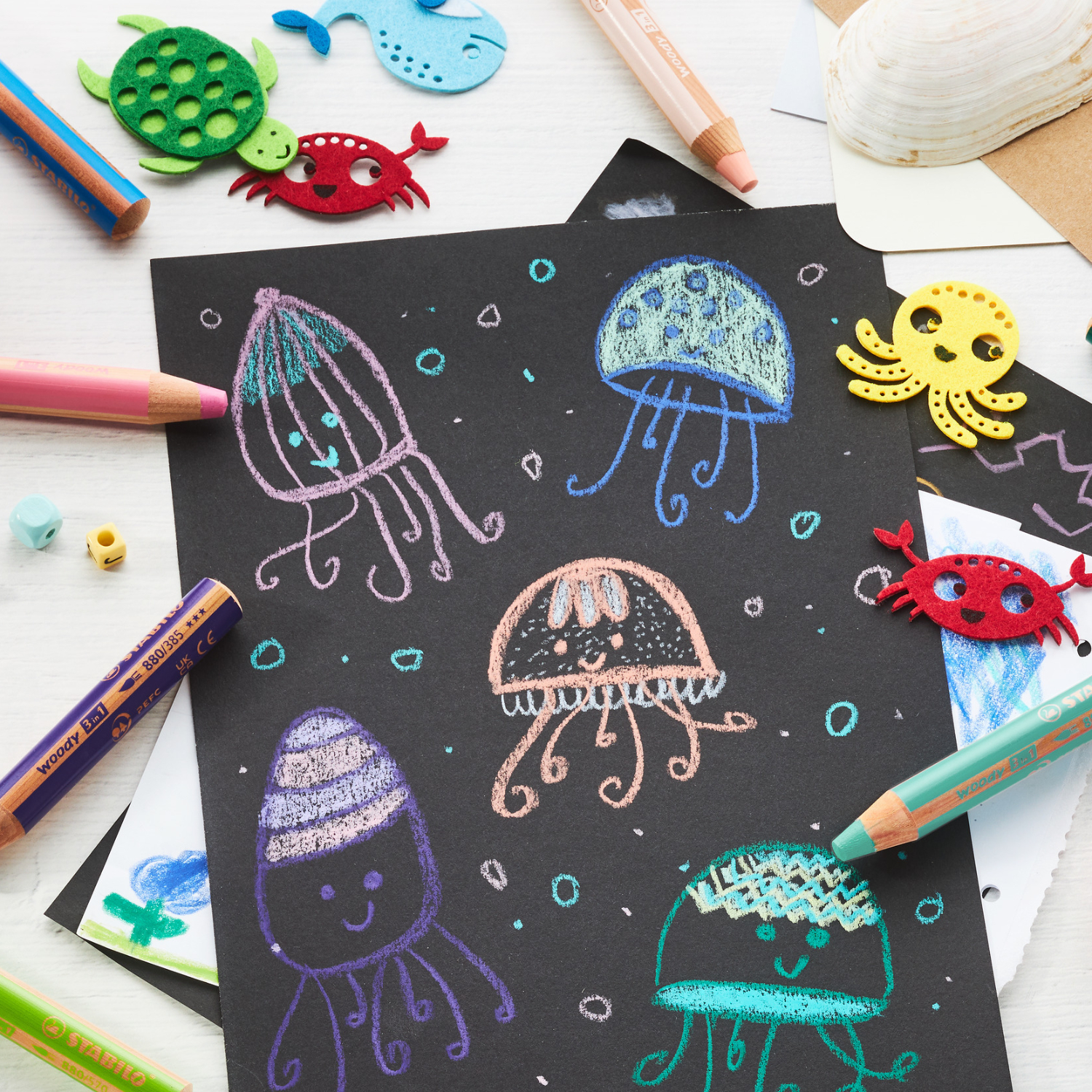 Woody im Etui: Bunte STABILO Stifte und Zeichnungen von Quallen auf schwarzem Papier, ideal für kreative Kinder.