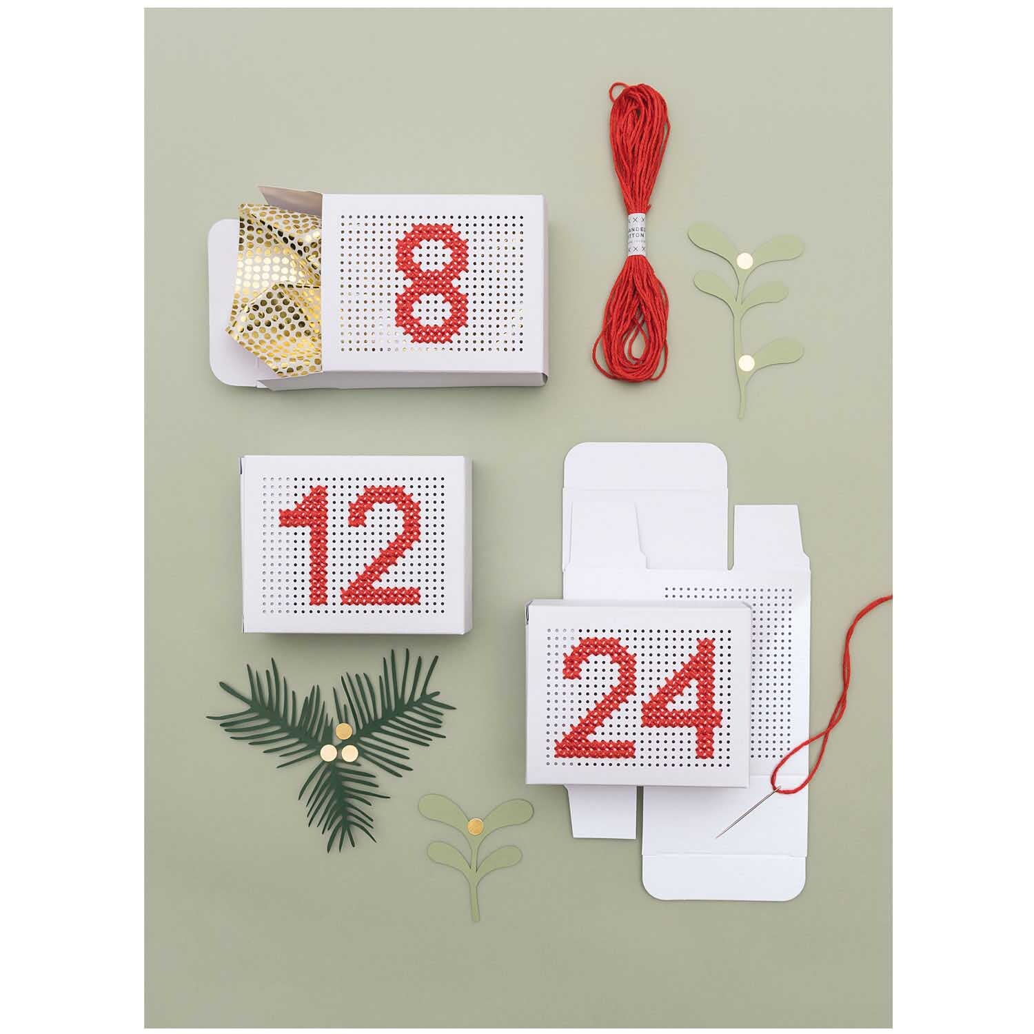 Paper Poetry Adventskalender Boxen zum Besticken zeigen weiße Boxen mit roten Zahlen und Stickgarn.