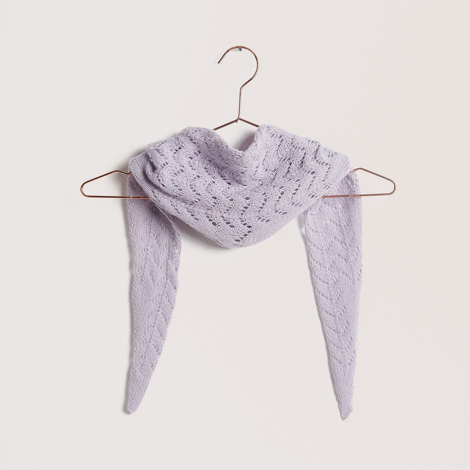 Strickset Mini-Dreieckstuch Modell 04a in zartem Flieder auf einem Kleiderbügel präsentiert.