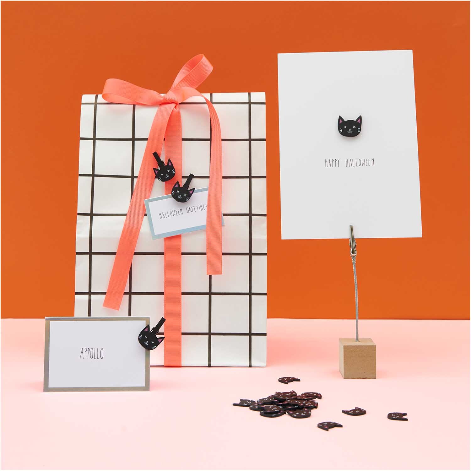 Holzstreu Katzen Mix schwarz 48 Stück, dekorativ auf Geschenk und Karten arrangiert, vor orangefarbenem Hintergrund.