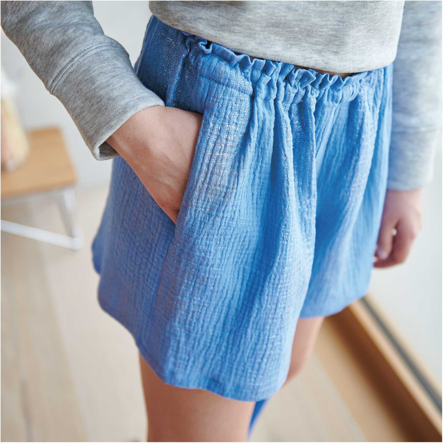 Meterware Krinkelmusselin azur Hot Foil von Rico Design: Person trägt azurblaue Shorts aus weichem Musselin-Stoff mit elastischem Bund.