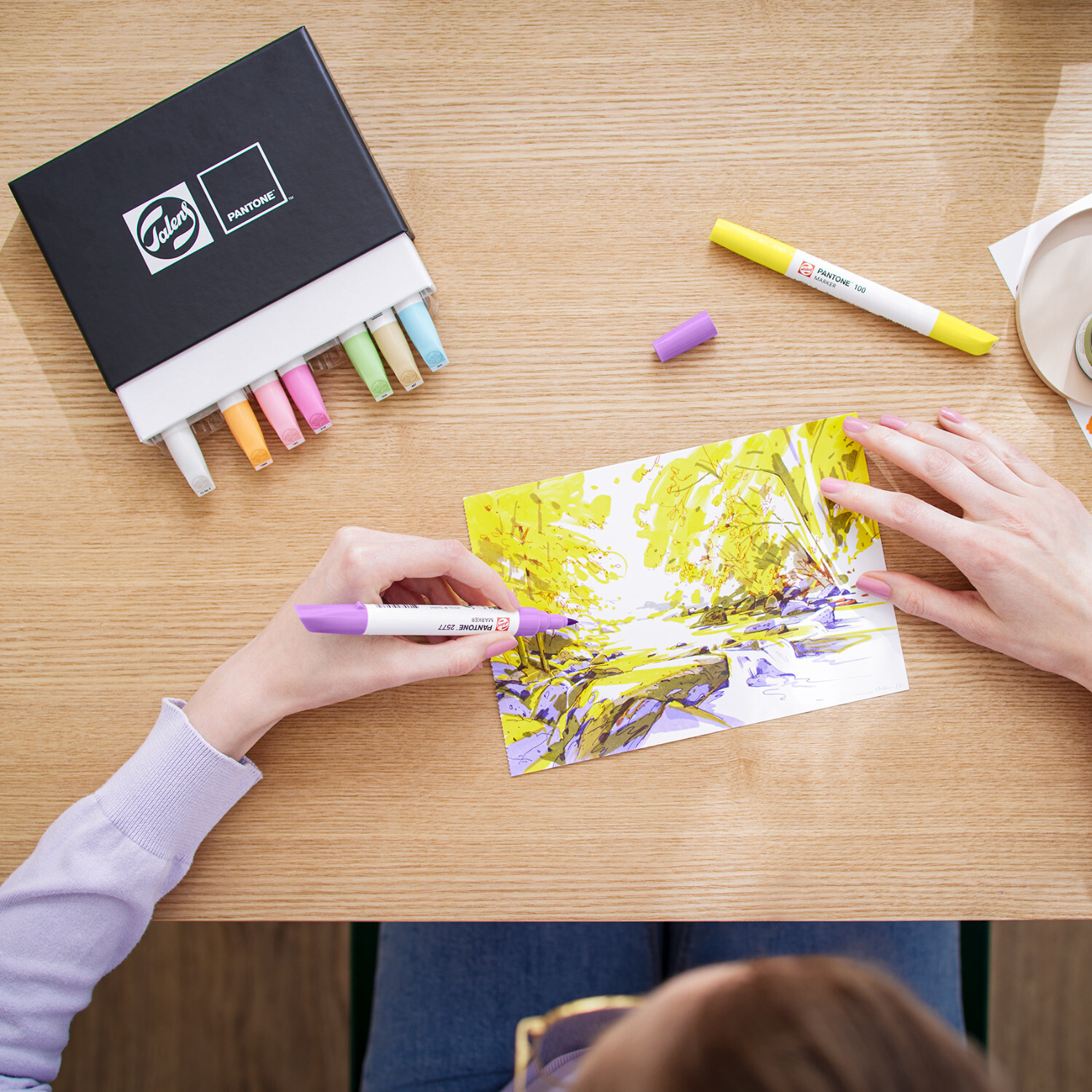 Talens | Pantone Marker Set pastel: Person malt mit pastellfarbenen Markern ein Landschaftsbild.
