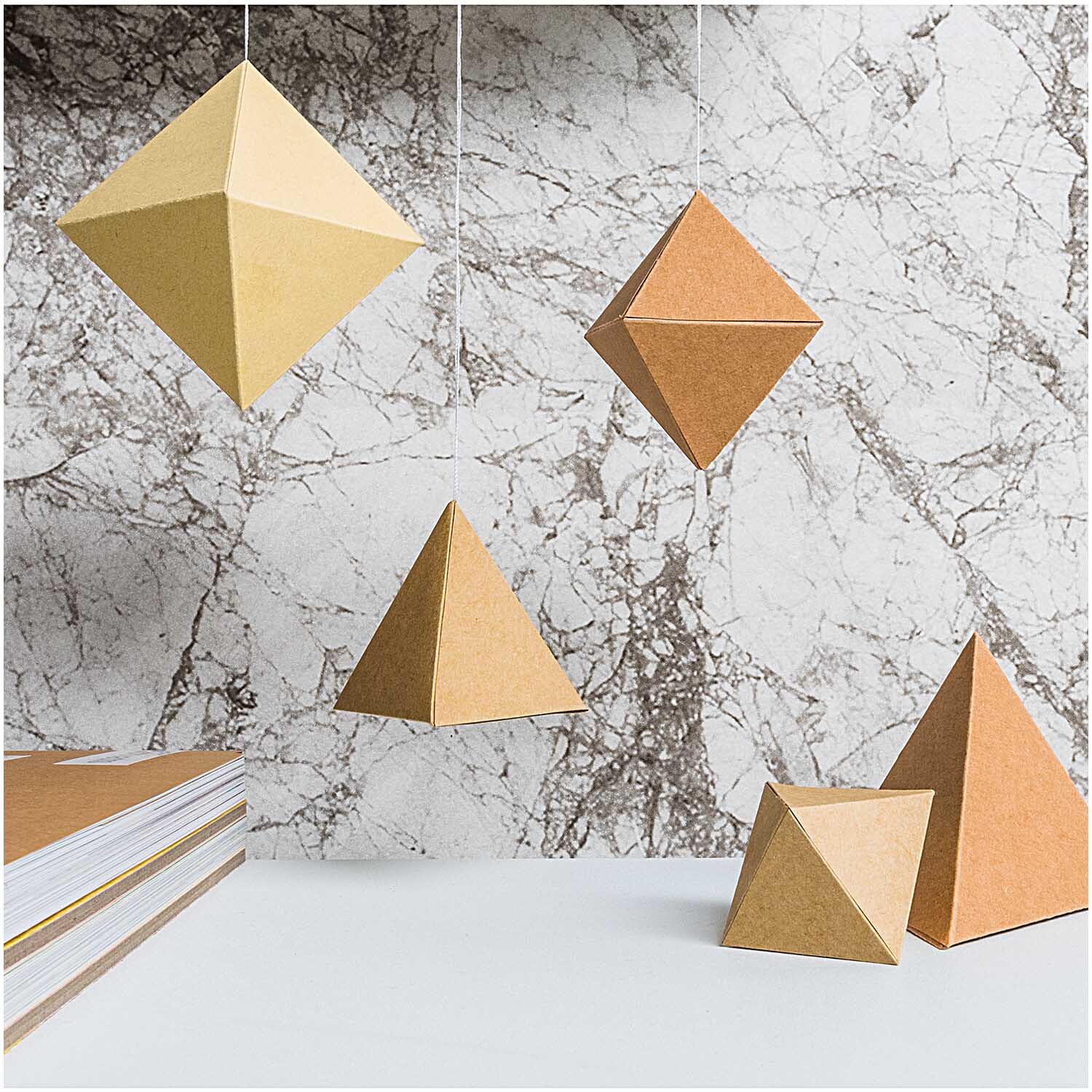 Paper Poetry Kraftpapier Block DIN A4 30 Blatt zeigt geometrische Formen aus braunem Papier vor einer Marmorwand. Ideal für kreative Bastelprojekte.
