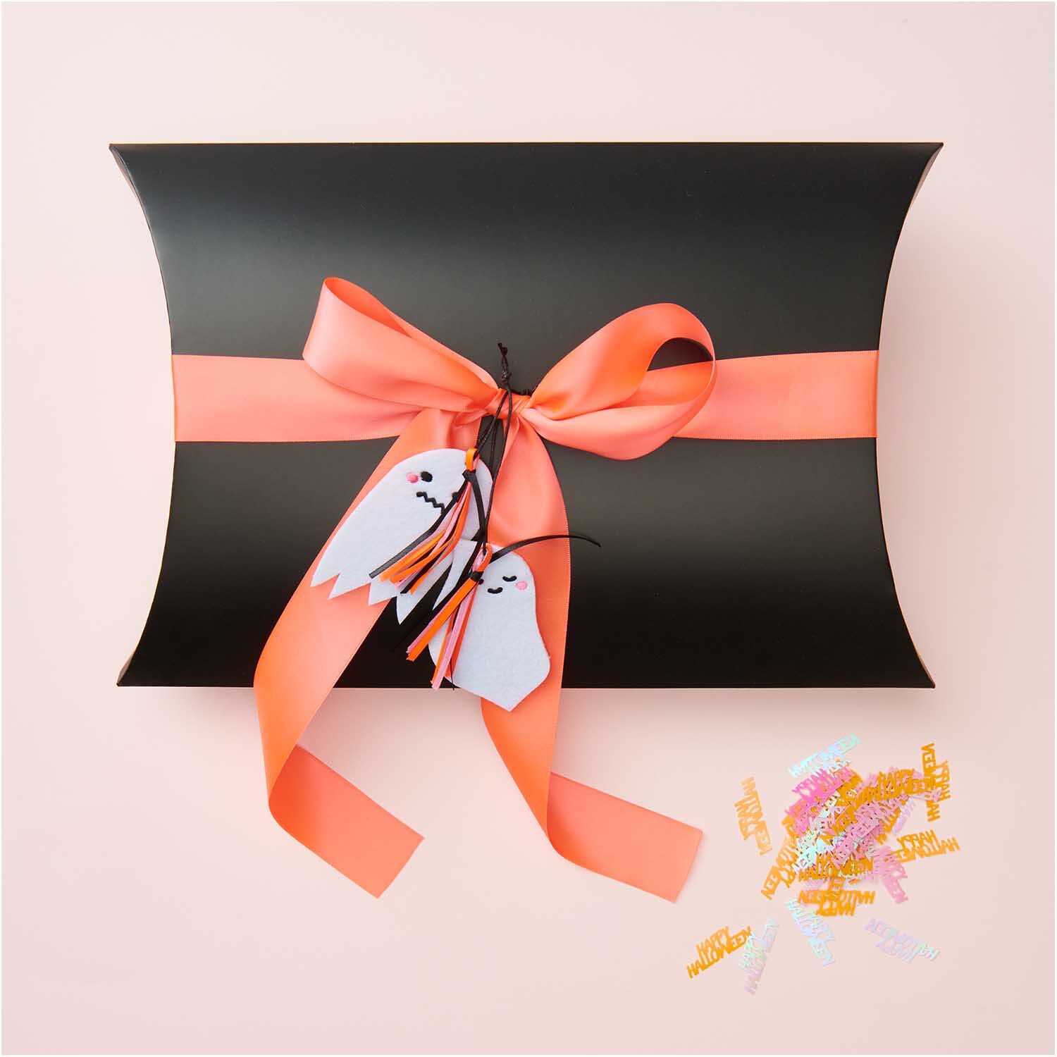 Filzhänger Gespenst freundlich weiß von Rico Design an schwarzer Geschenkbox mit orangener Schleife.