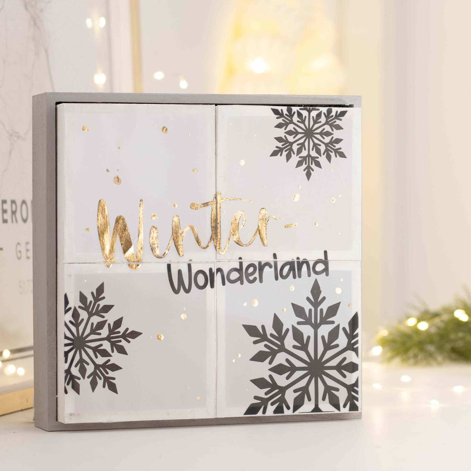 Inspiration Winter-Lichtbox zeigt weiße Kacheln mit goldener Schrift und schwarzen Schneeflocken.
